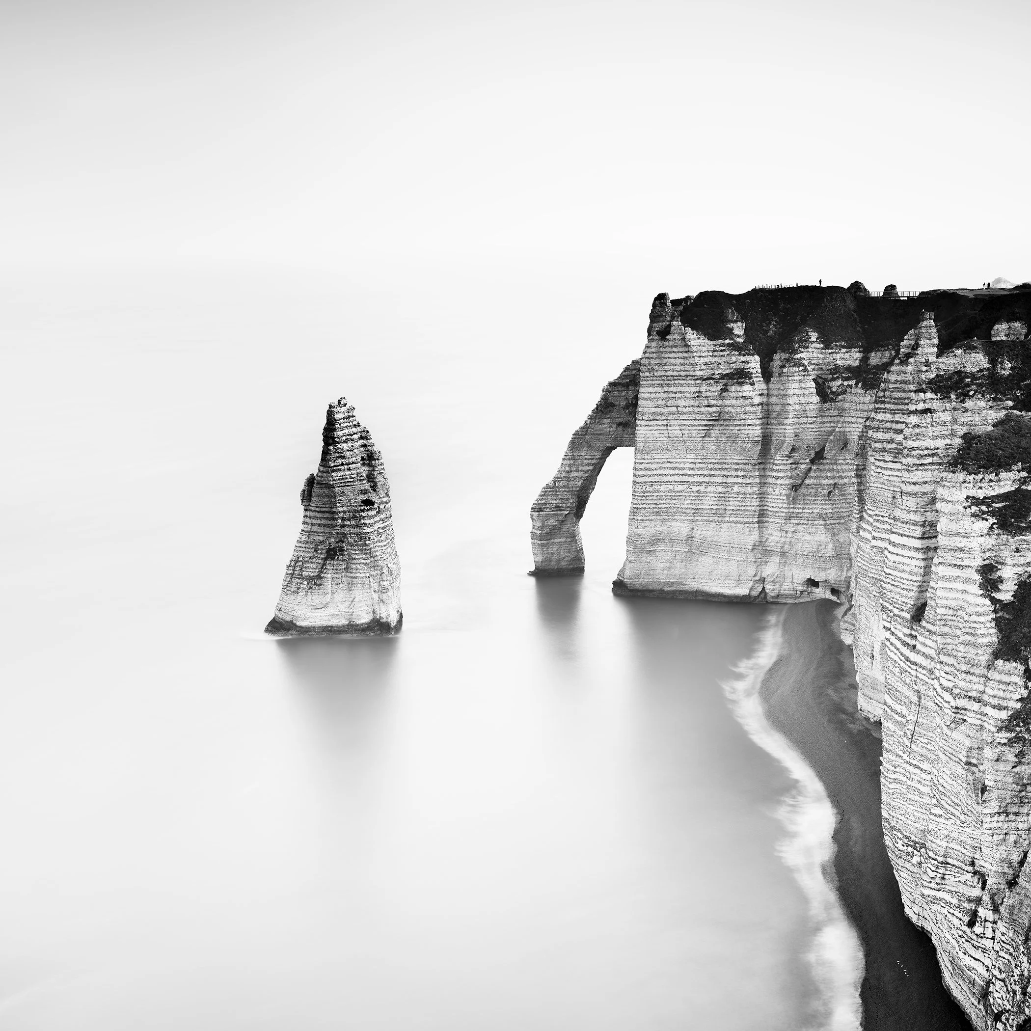 Black-and-white long-exposure photograph of Étretat chalk cliffs and sea stack, France, by Gerald Berghammer