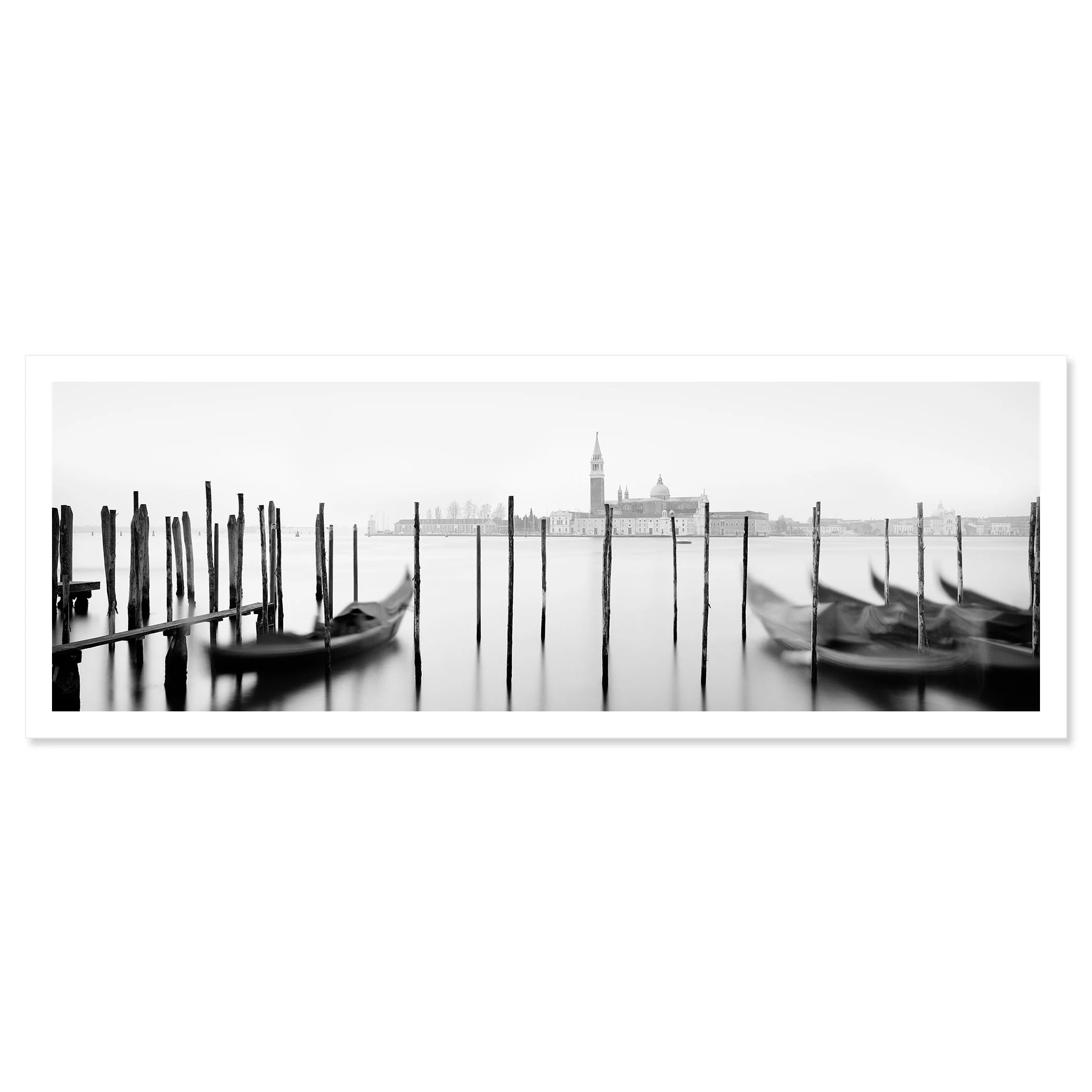 Gerald Berghammer - Black and white cityscape photography. Gondolas moored along wooden posts on a canal with view of a city skyline and a tall bell tower. Fine art print only