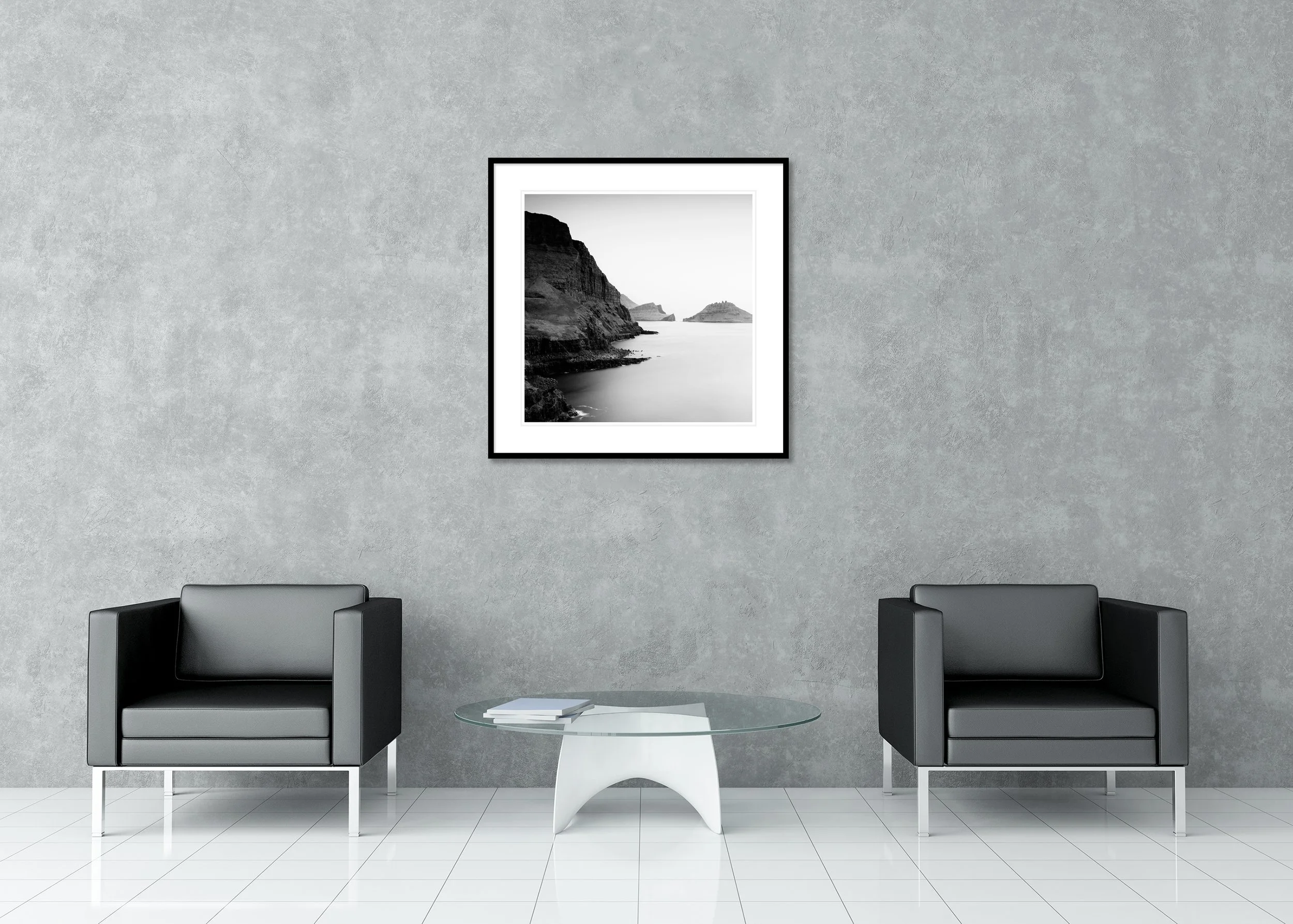 Black and white long exposure of a rocky coastline with towering cliffs and quiet sea, archival pigment print in a classic frame with a mount.