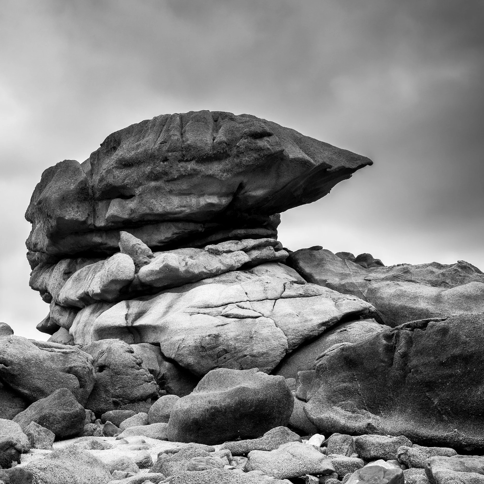 Cropped detail of Pink Granite Coast Panorama Study 1 showing layered granite structures beneath dramatic clouds in Brittany, France.
