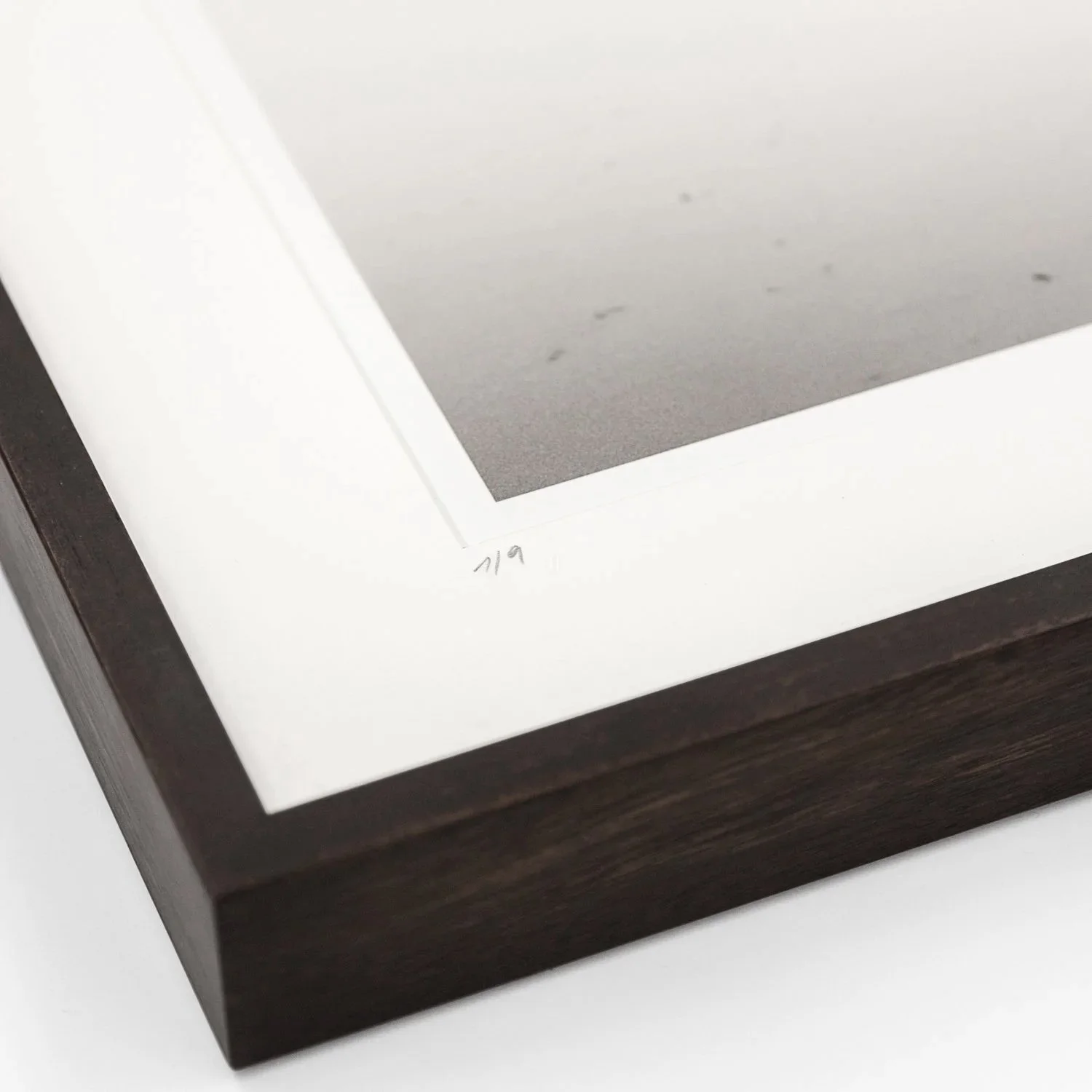 Close-up of the handwritten edition number 1/9, white archival mount and dark-brown wooden frame by Gerald Berghammer.