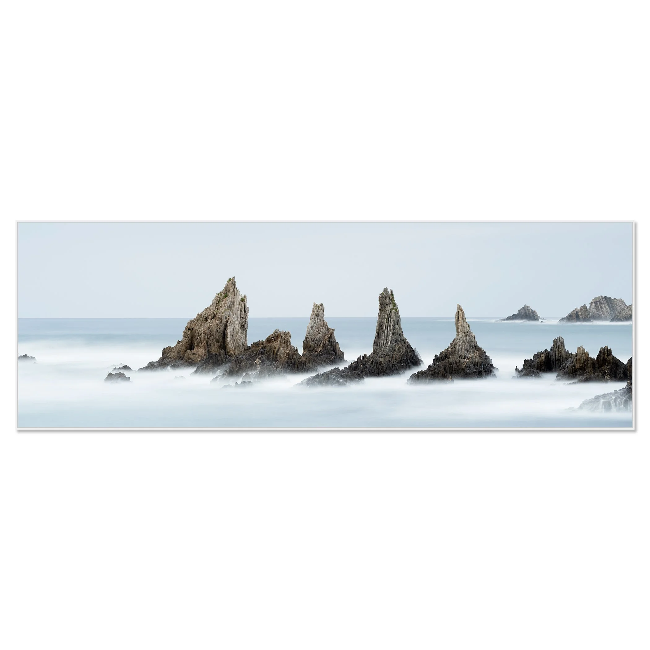 © 2023 Gerald Berghammer - Color seascape. Long exposure photograph of jagged sea stacks rising from the ocean with misty water and a light sky in the background. Chromaluxe framed white
