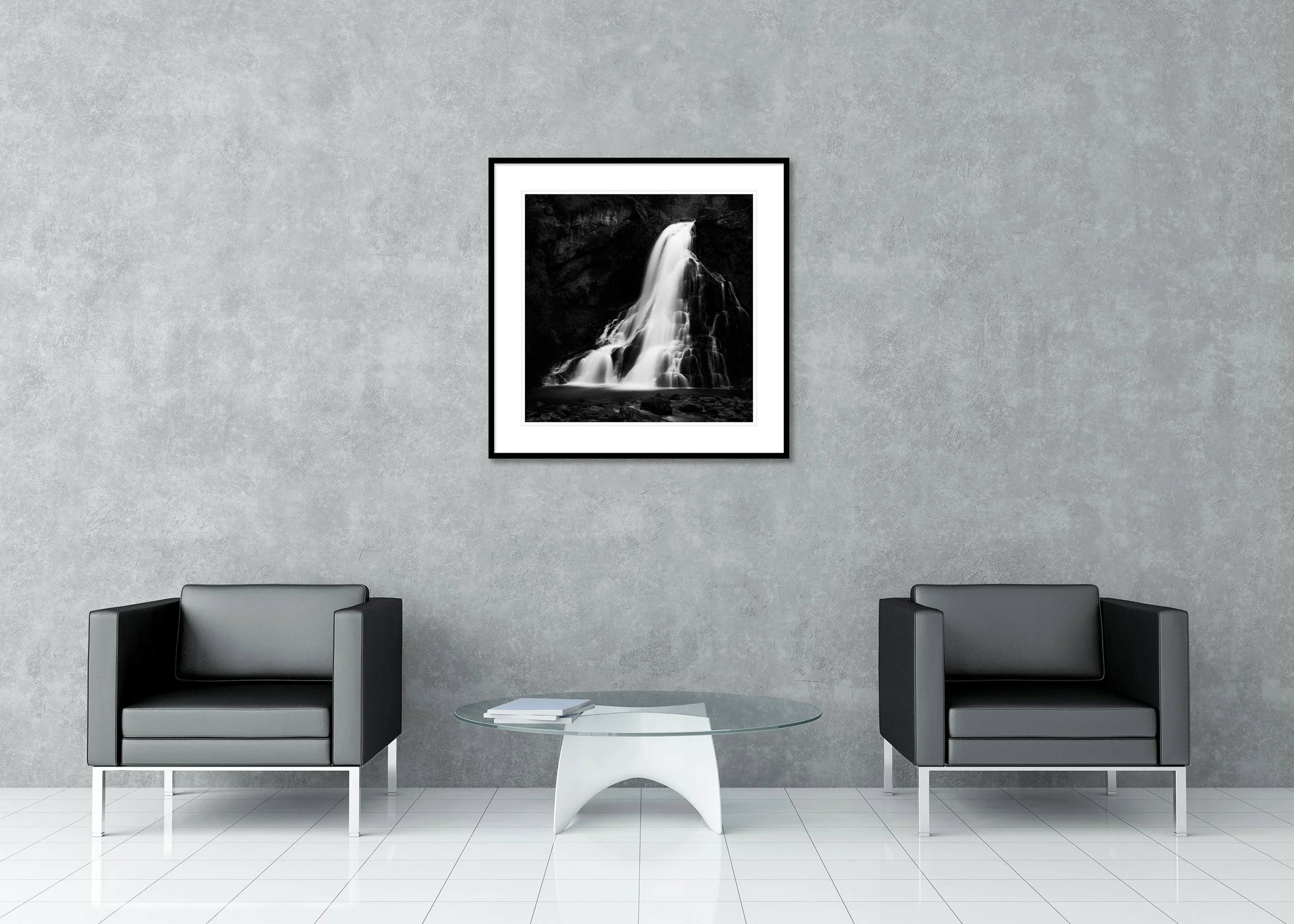 Black-and-white long-exposure waterfall over dark rocks into a calm pool, archival pigment print in a classic frame with a mount.