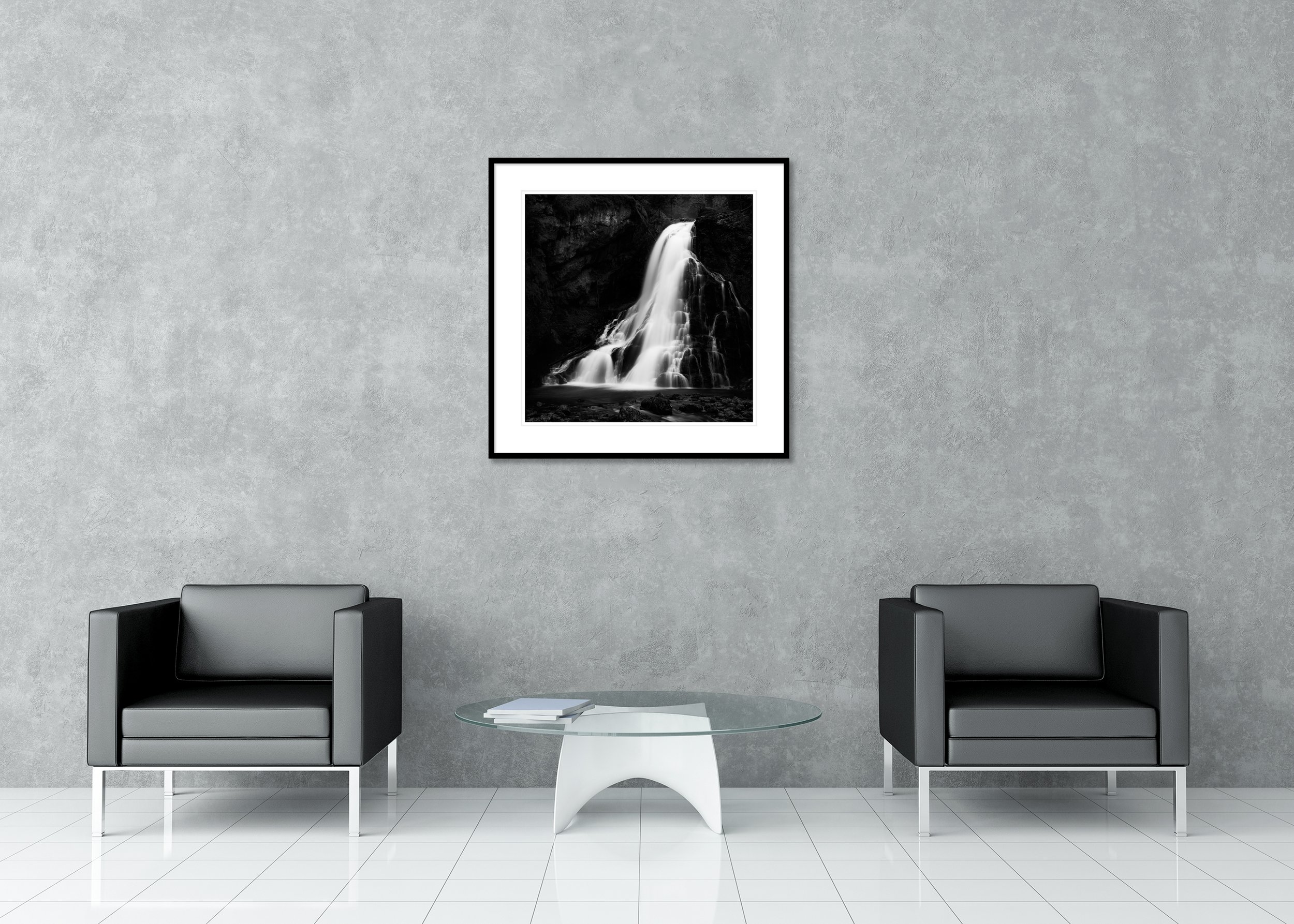 Black-and-white long-exposure waterfall over dark rocks into a calm pool as an archival pigment print with passe-partout in a classic frame
