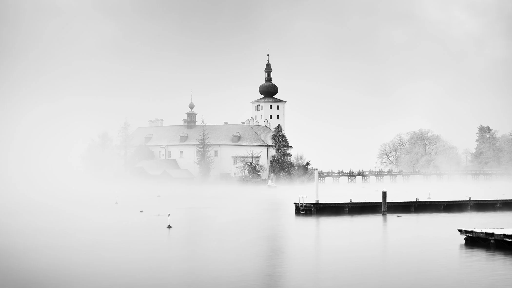 Seeschloss Ort, Study 3 – panoramic black-and-white view of the castle, footbridge and jetties in winter mist on Lake Traunsee.