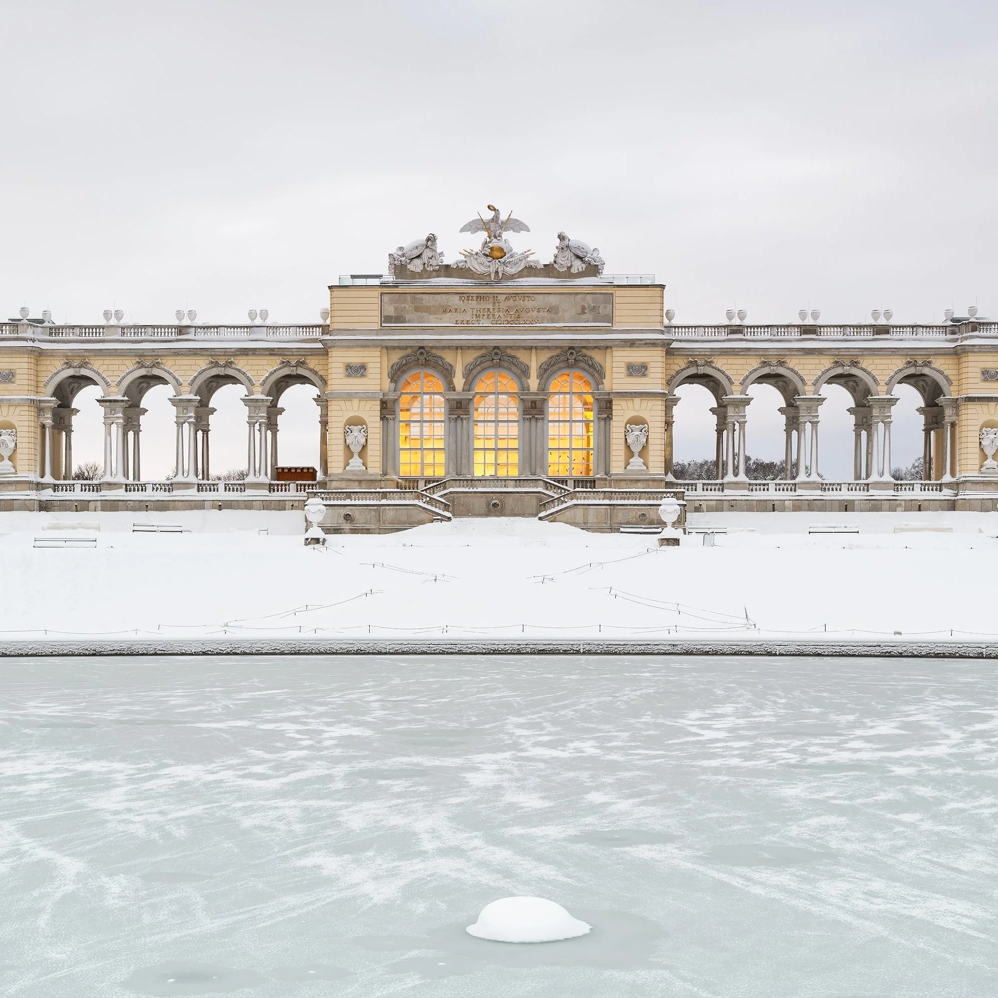 Gerald Berghammer - Color Photography. A historic building on a snow-covered landscape, surrounded by leafless trees, with a frozen body of water. Print detail 3