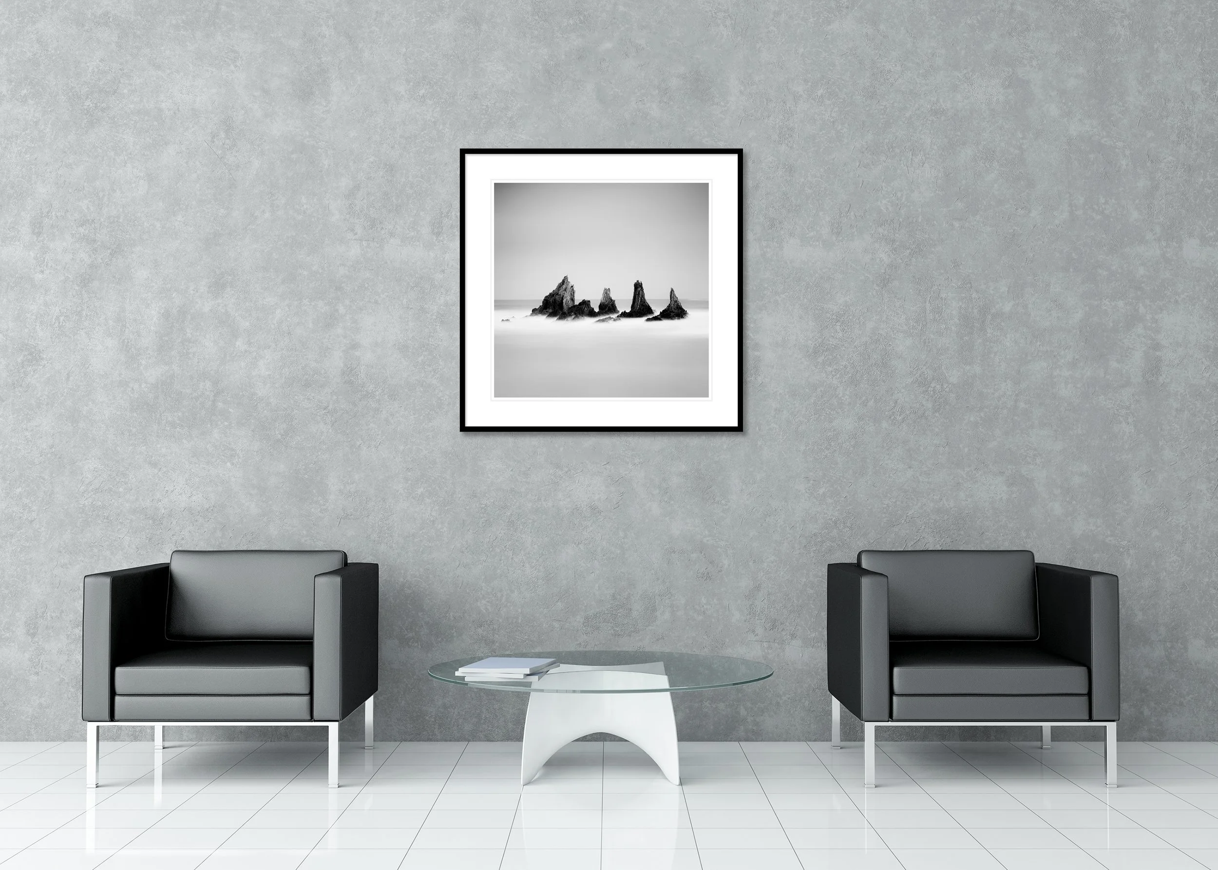 Archival pigment print in a classic frame with passe-partout showing a black and white Atlantic seascape with five sharp sea stacks, tranquil water, and an open, cloudless sky.