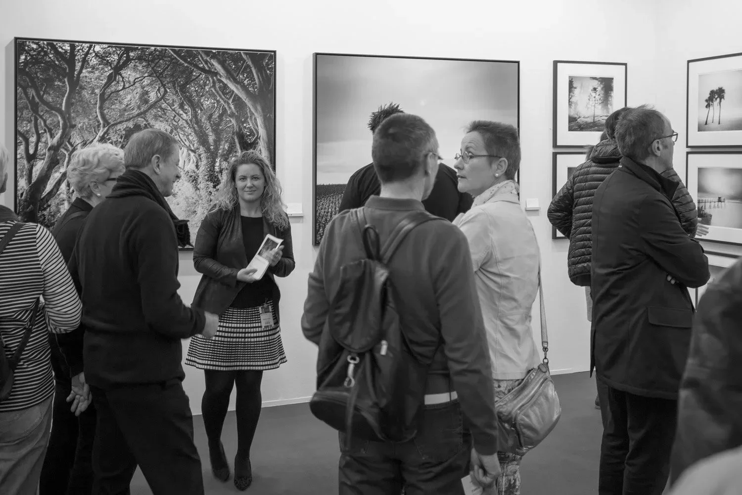 Art fair visitors viewing large black-and-white tree and landscape photographs by Gerald Berghammer at art KARLSRUHE 2017.
