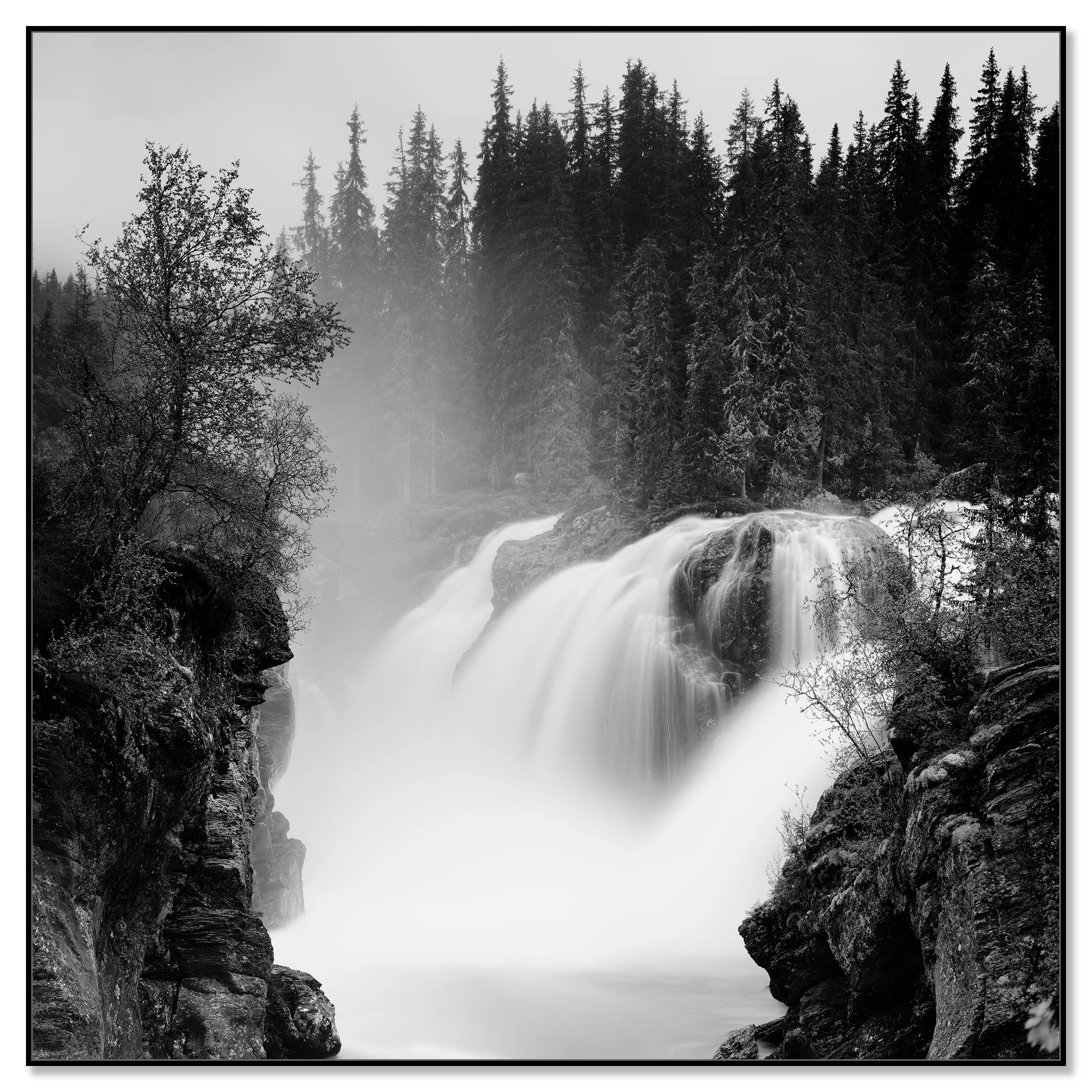 Black and white photo of a powerful waterfall flowing through a rocky forest gorge – framed ArtBox black
