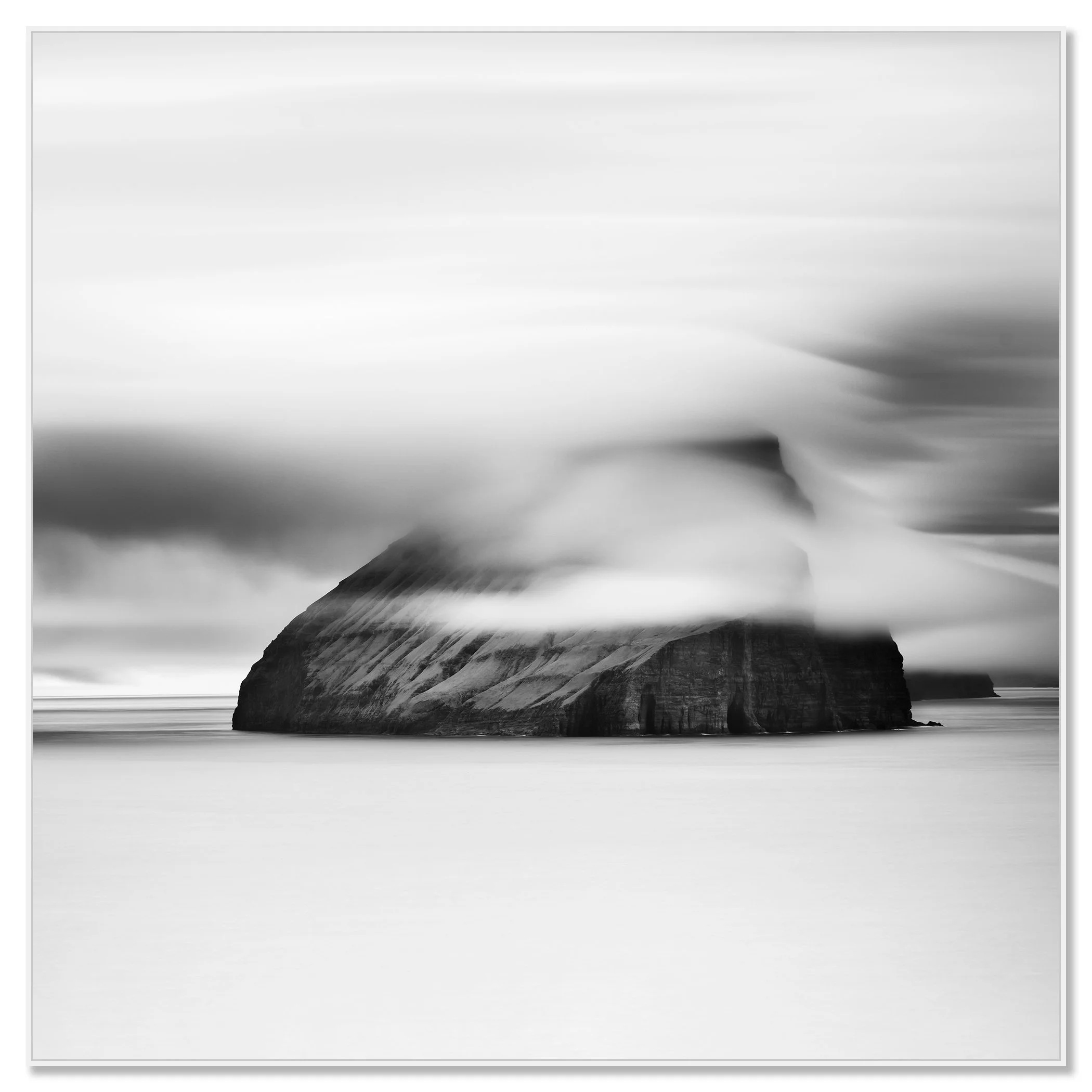 Minimalist monochrome seascape with a large sea stack, low cloud and smooth water – framed ArtBox white