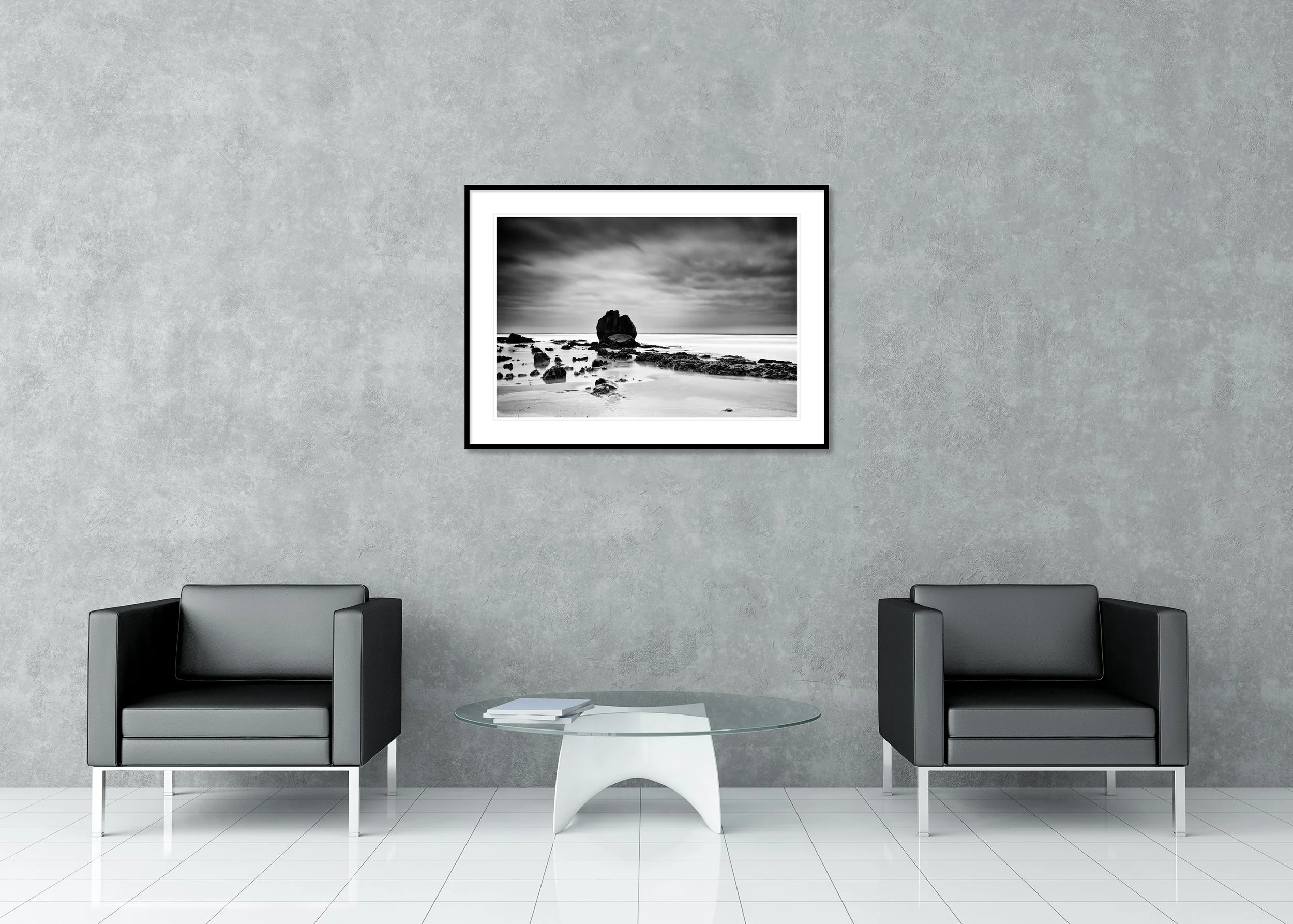 Dramatic black-and-white seascape with textured coastal rocks beneath a stormy sky, archival pigment print in a classic frame with a mount.