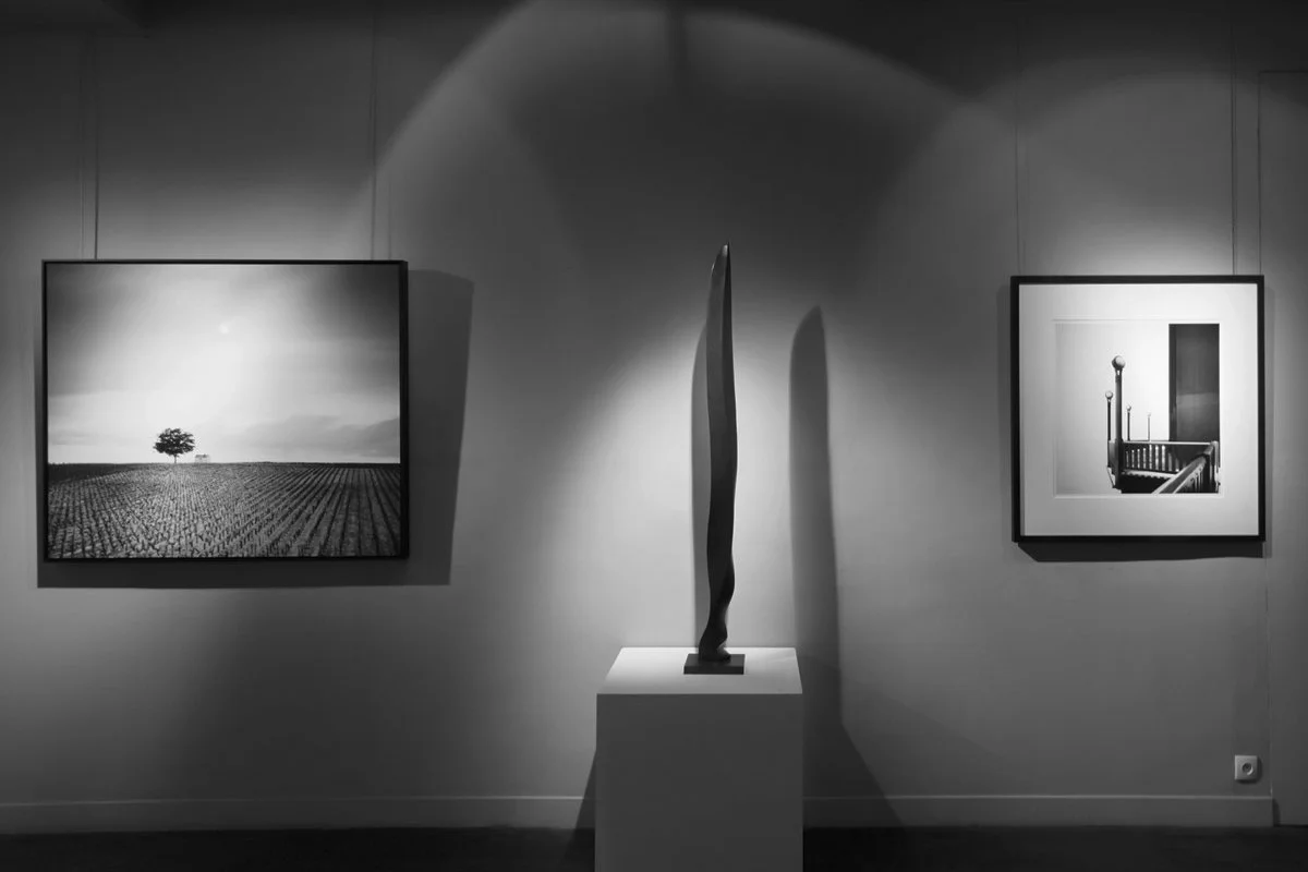 Framed minimalist black-and-white landscape and architectural photographs by Gerald Berghammer displayed beside a sculpture at Galerie Arnoux, Paris.