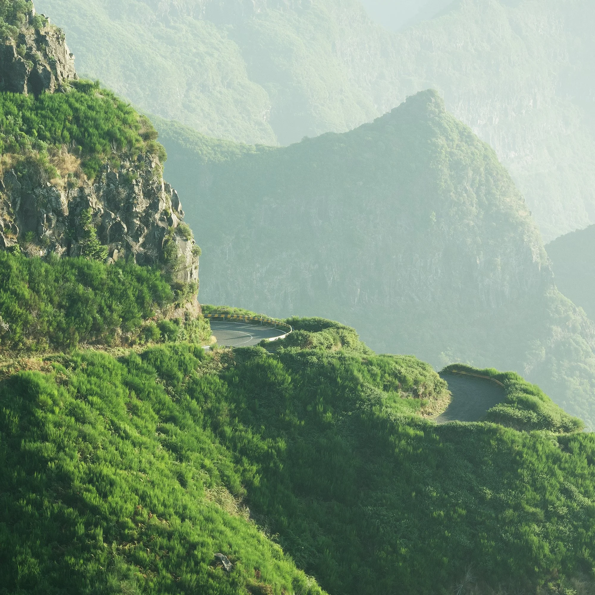© 2021 Gerald Berghammer - Color Fine Art Landscape Photography. A winding mountain road through lush green cliffs and misty mountains in the background. Print detail 3