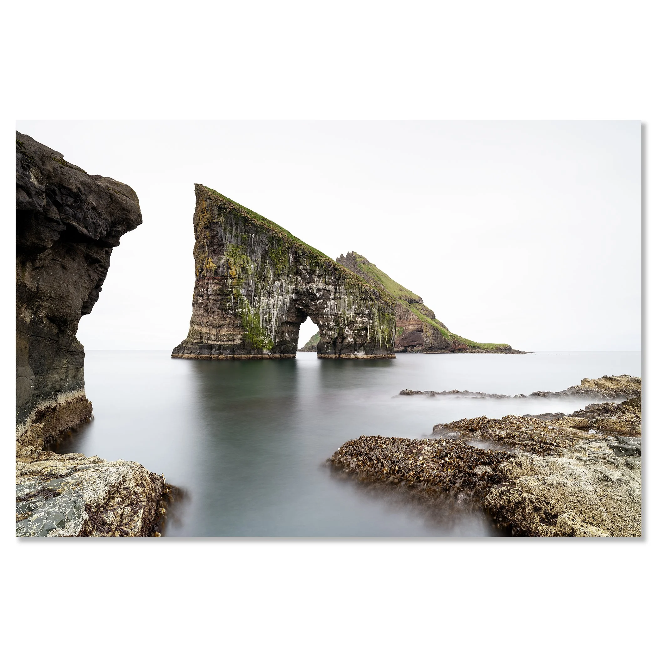 Gerald Berghammer Fine Art Color Photography - Rock formation with a natural sea arch near the water, green grass on top, surrounded by rocky shoreline. Chromaluxe frameless