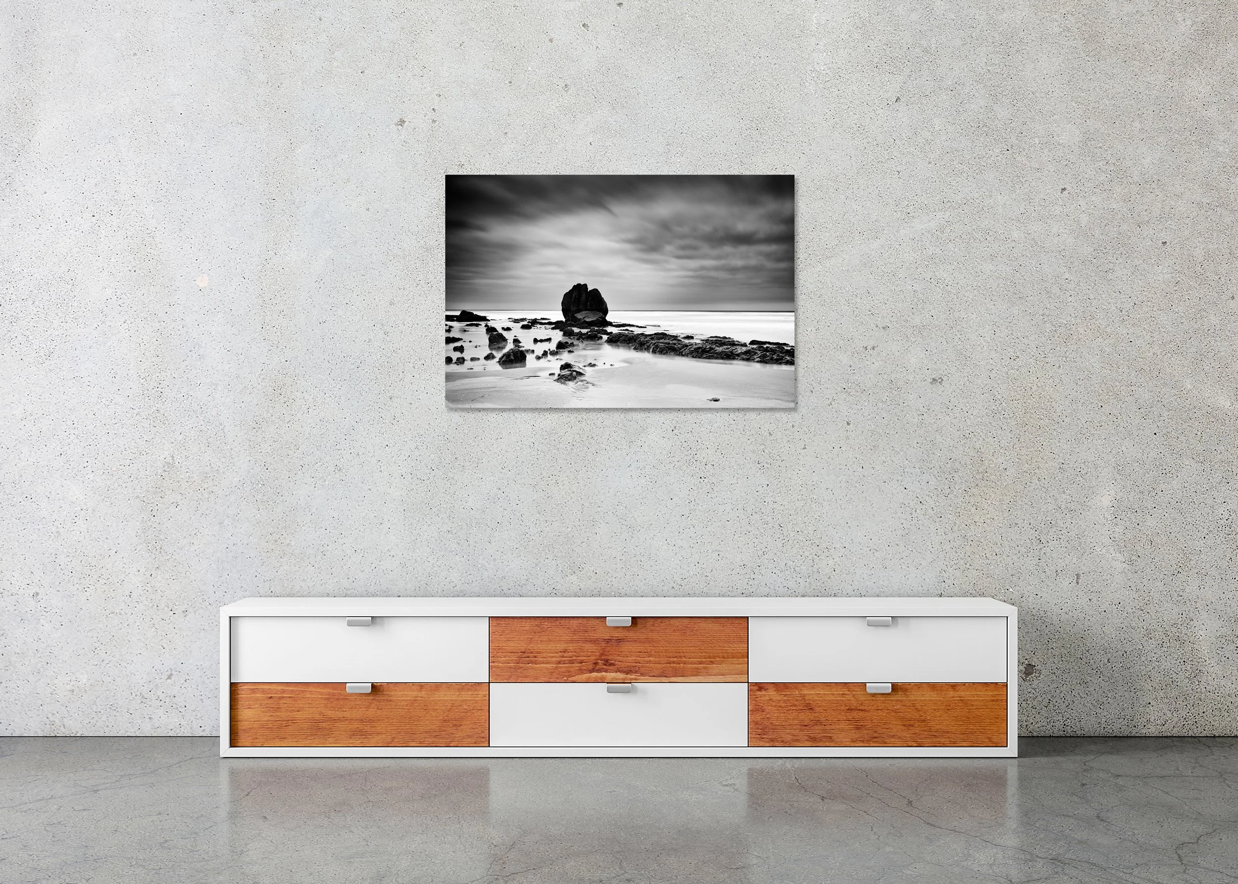 Dramatic black-and-white seascape with textured coastal rocks beneath a stormy sky, photo print mounted on Dibond, frameless.