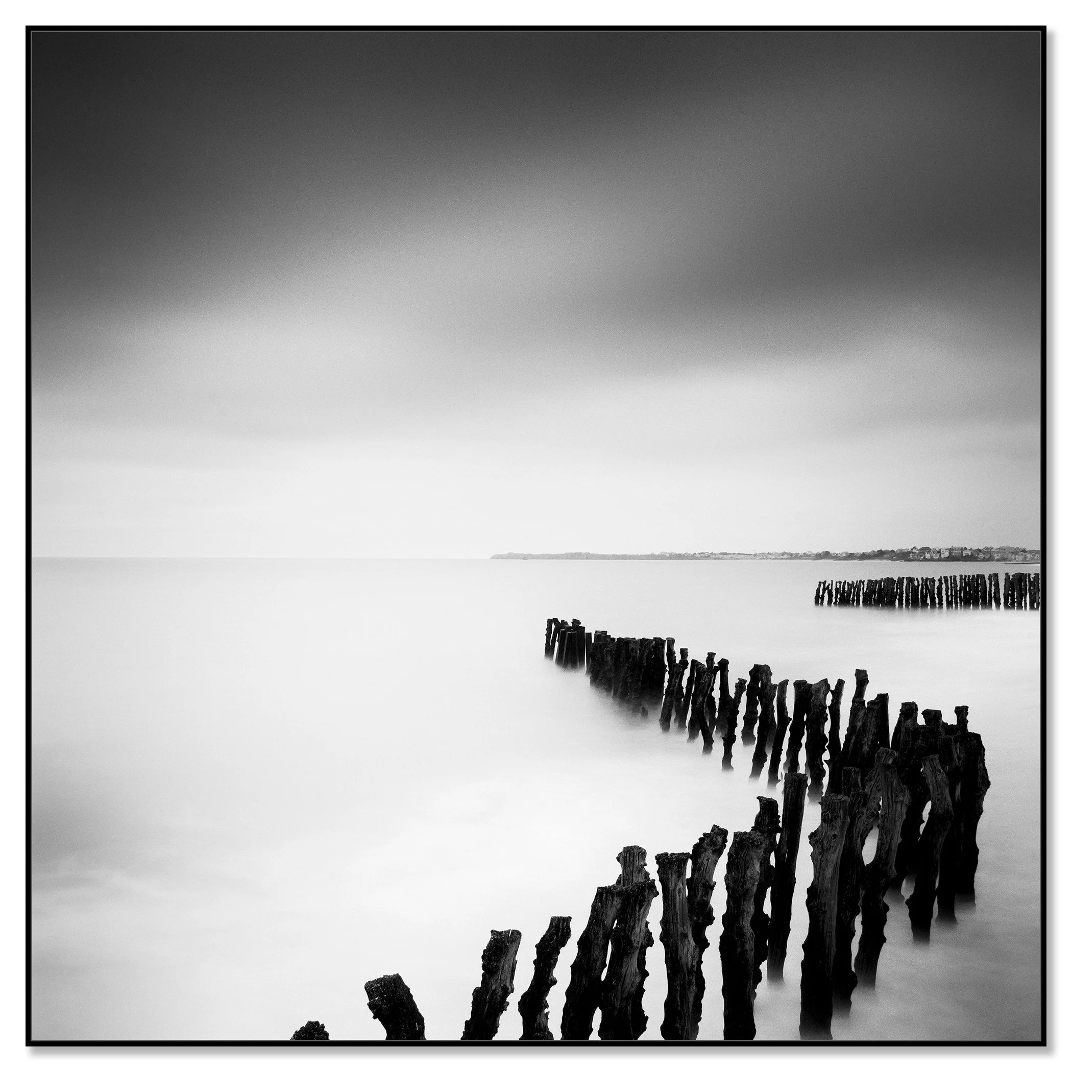Monochrome long exposure seascape with wooden groynes, soft sea and distant shoreline – framed ArtBox black
