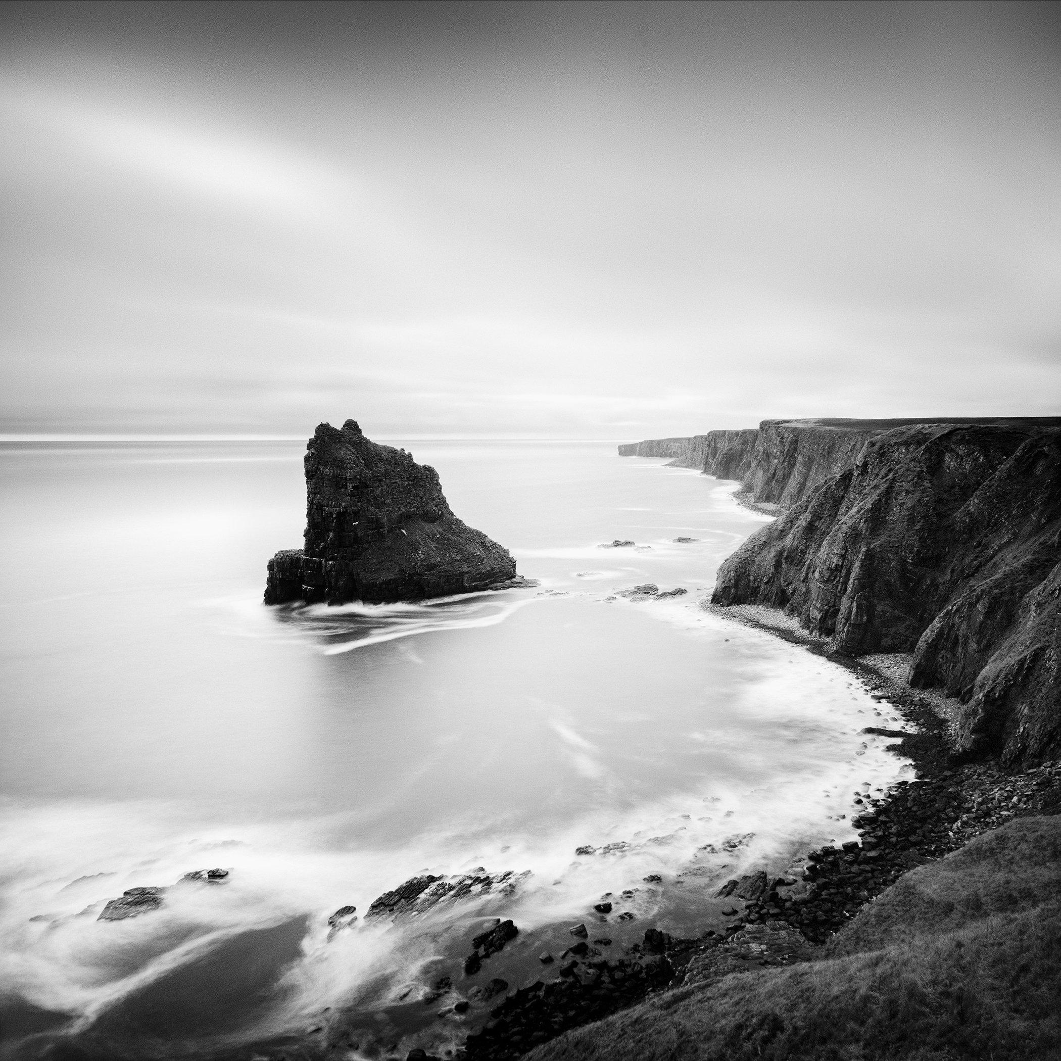 Black-and-white long-exposure seascape of steep Scottish cliffs and a solitary sea stack by Gerald Berghammer.