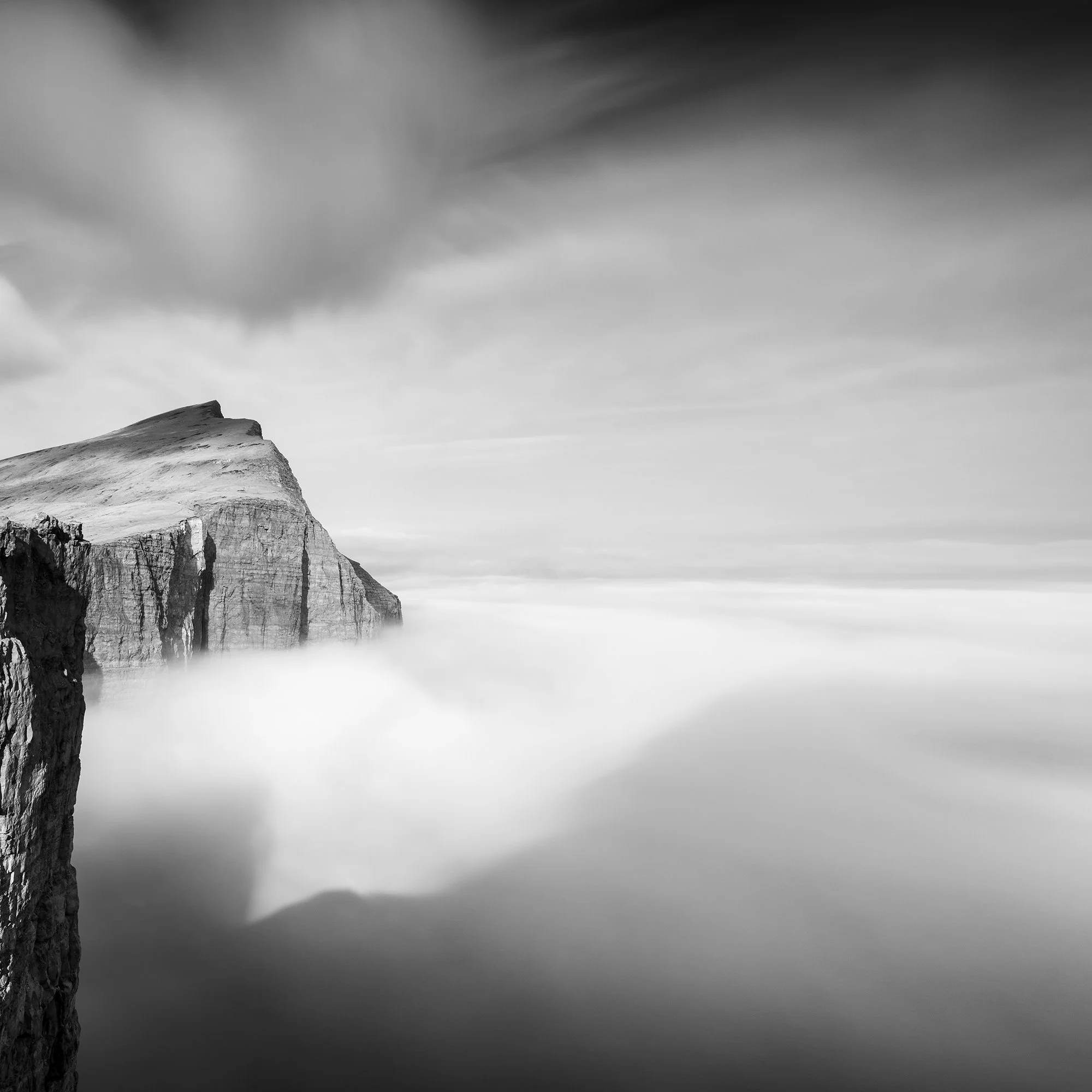 Detailed crop of Trælanípa emerging from mist beneath a blurred sky in the Faroe Islands, by Gerald Berghammer.