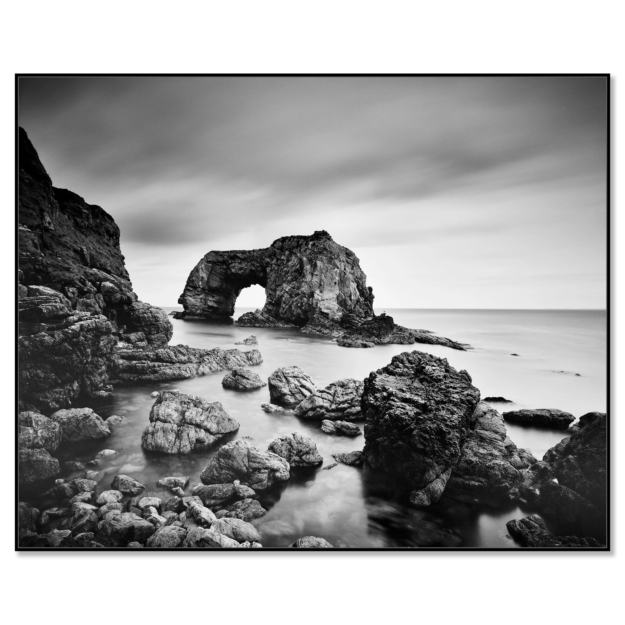 Black-and-white long exposure of Great Pollet Sea Arch surrounded by rocky shoreline and calm sea – framed ArtBox black
