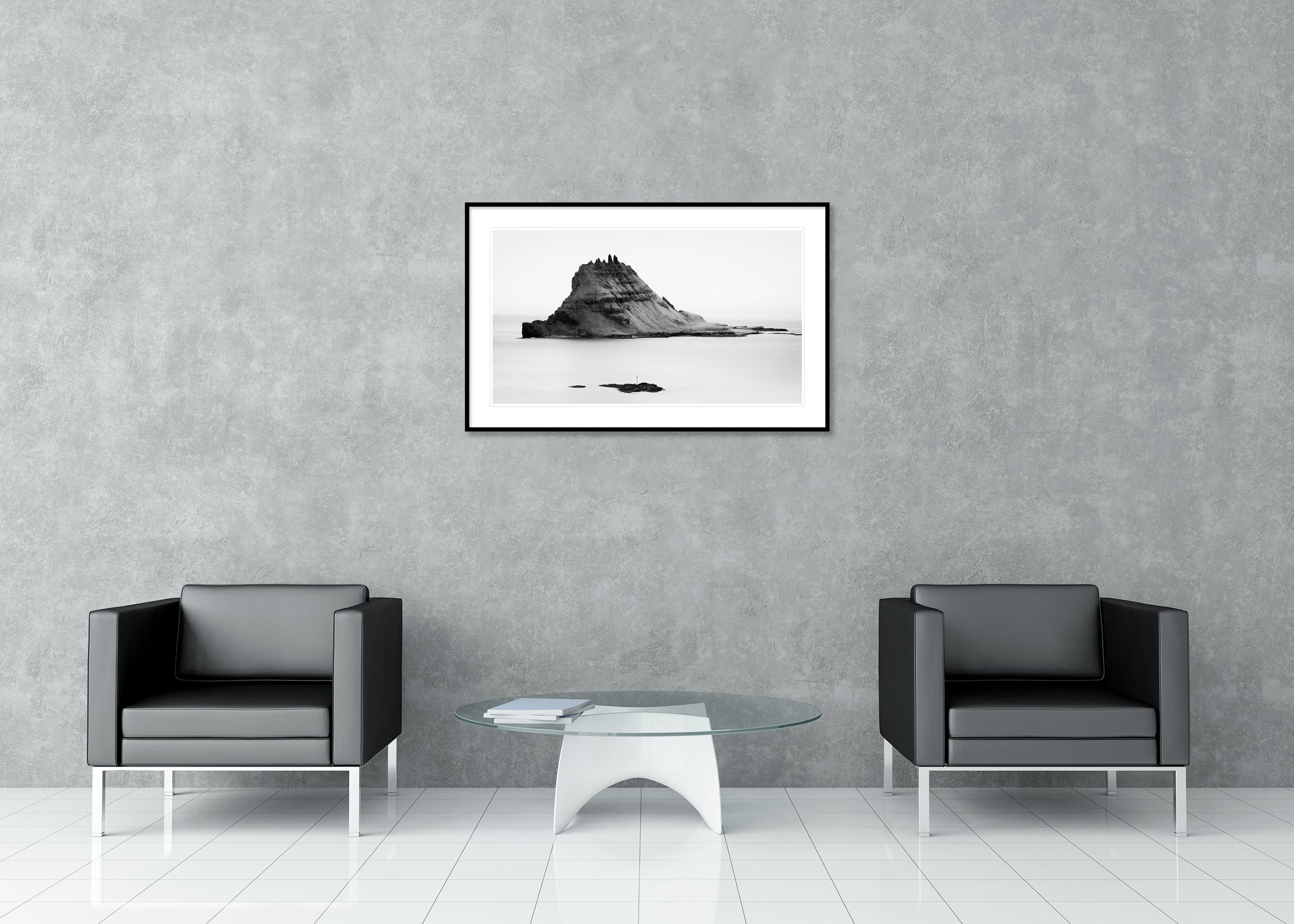 Black and white long-exposure photograph of a rugged rocky island rising from a calm sea under a minimalist sky. Archival Pigment Print – Classic Frame with Passe-Partout