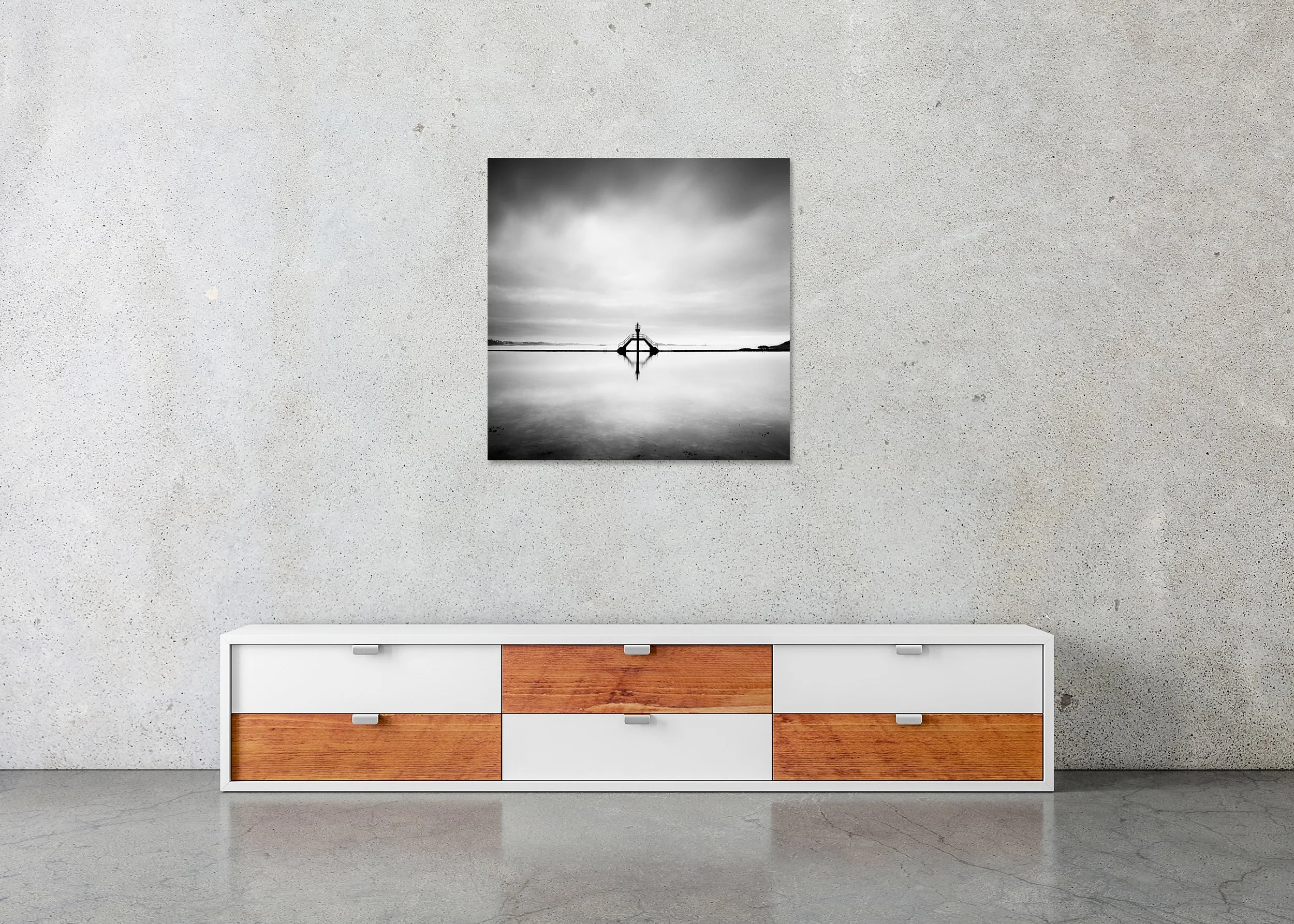 Minimalist seascape with a symmetrical diving platform reflected in still water under a cloudy sky, photo print mounted to Dibond, frameless.