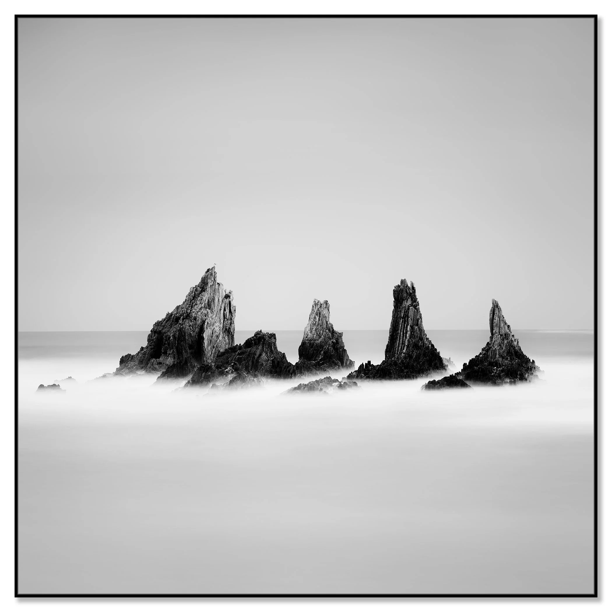 Rocky Peaks Study 1 by Gerald Berghammer, black-and-white seascape of sea stacks in Spain, mounted on aluminium Dibond in a black ArtBox frame.