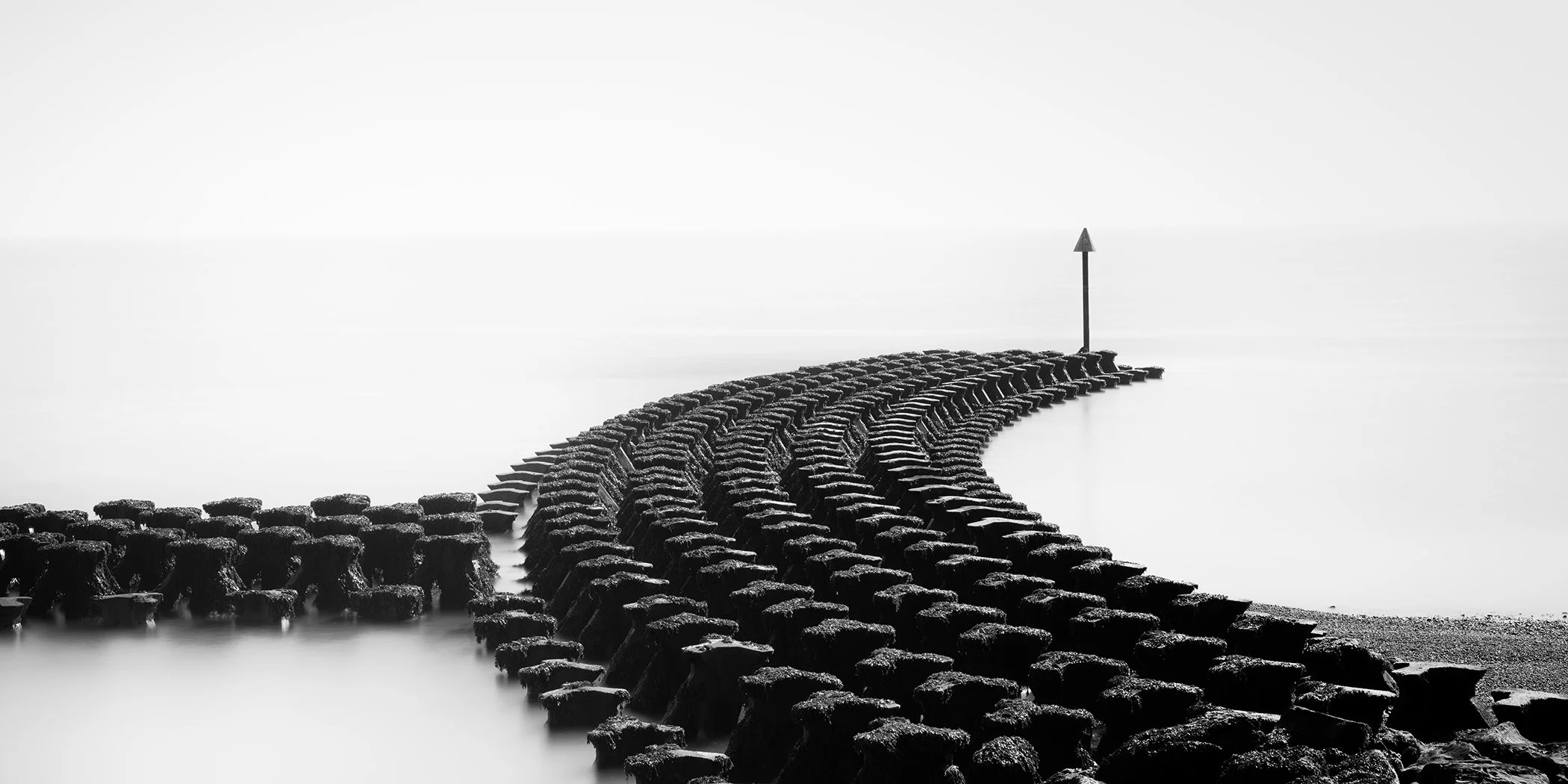 Cobbolds Point Panorama Study 2, minimalist black-and-white seascape with a curved breakwater in Felixstowe, England, by Gerald Berghammer.