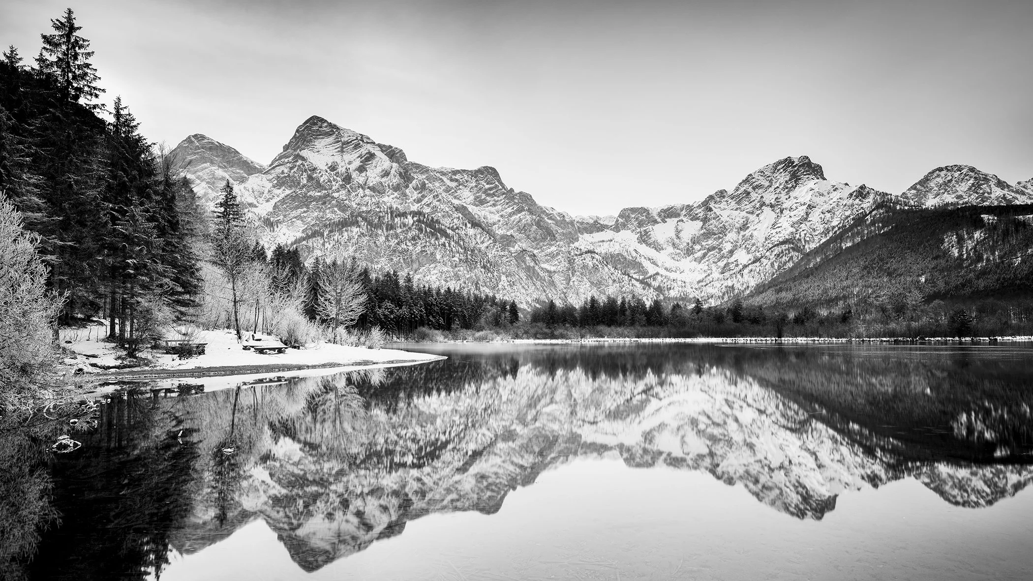 White Mountains, Almsee, Austria, black-and-white fine art photograph by Gerald Berghammer showing snow-covered Alpine peaks reflected in calm water.