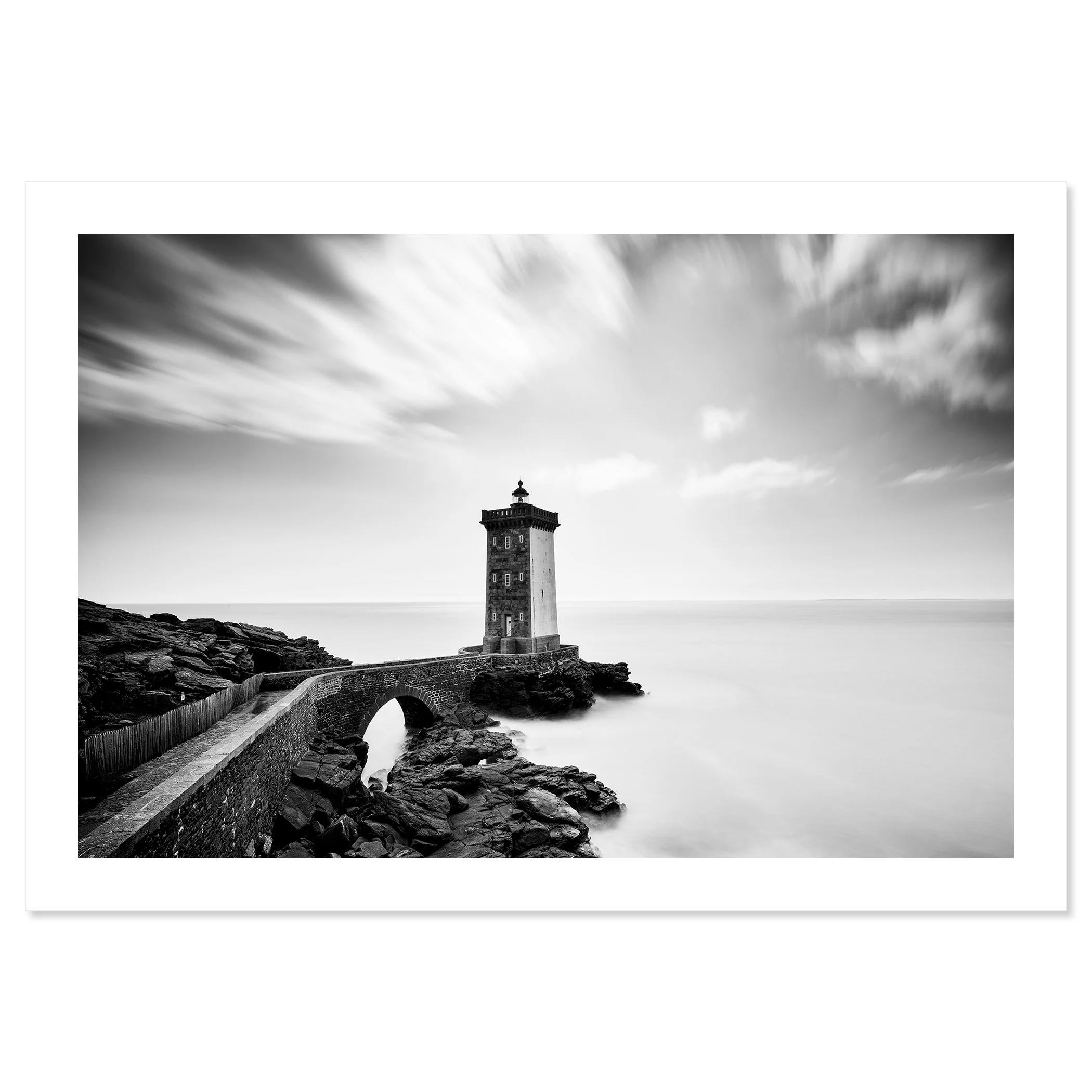 Black-and-white coastal lighthouse with stone bridge across rocks and overcast sky, Print only