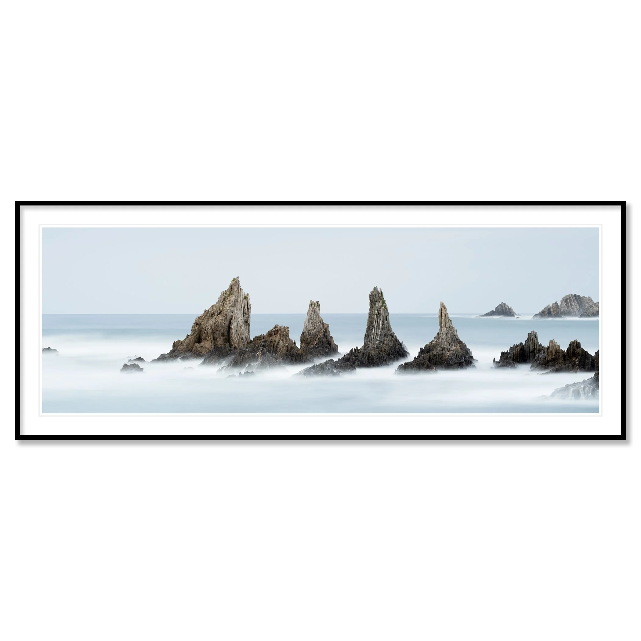 © 2023 Gerald Berghammer - Color seascape. Long exposure photograph of jagged sea stacks rising from the ocean with misty water and a light sky in the background. Classic framed black