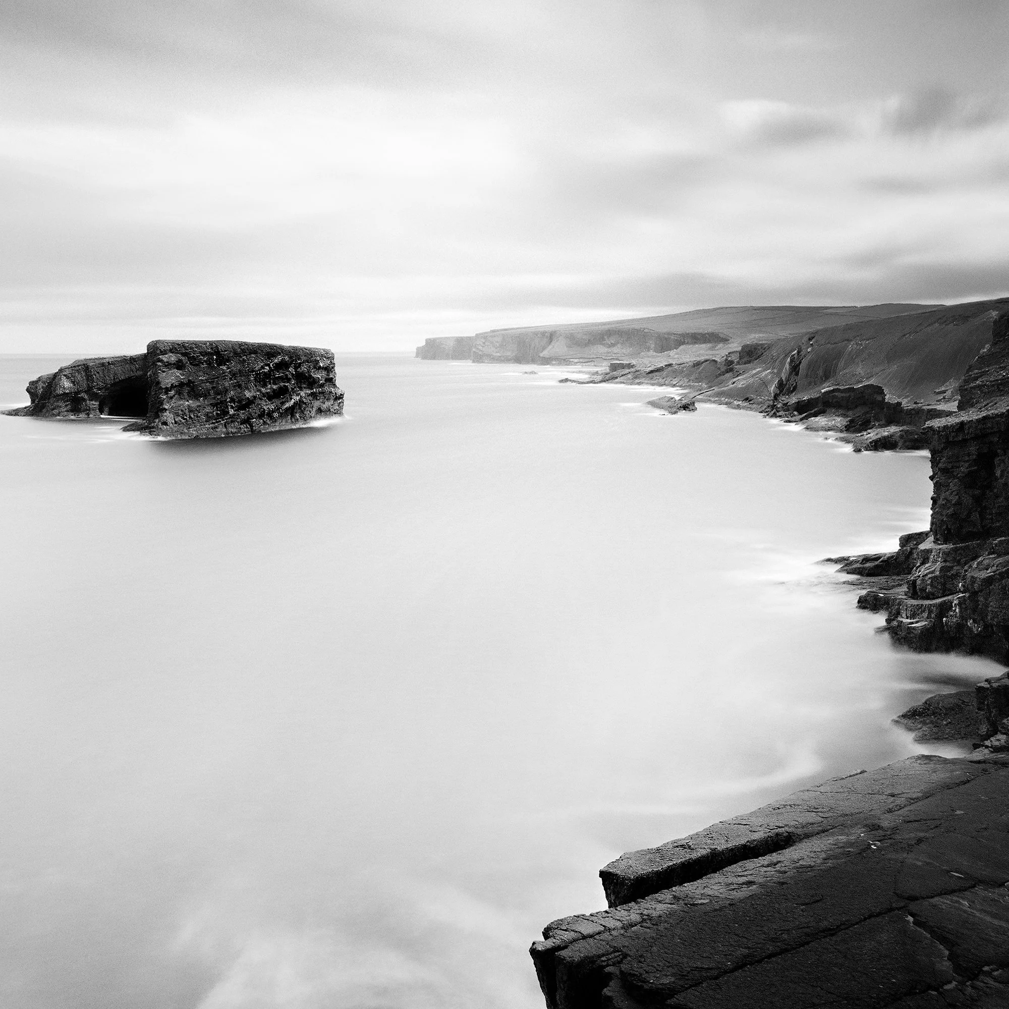 Gerald Berghammer - Black and white long exposure seascape photography. Rocky coastal landscape with cliffs and a large rock formation in the ocean. Print detail 2