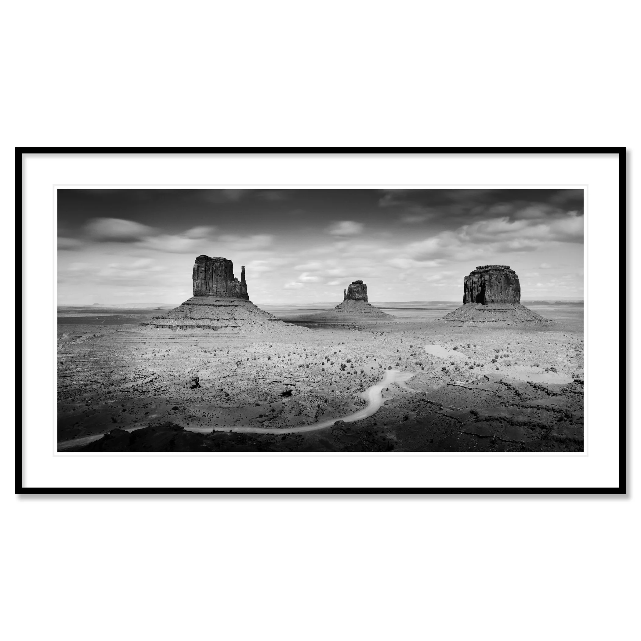 © 2015 Gerald Berghammer - Black and white photo. Large rock formations in a desert landscape, with a winding dirt road in the foreground and a cloudy sky above. Classic framed black