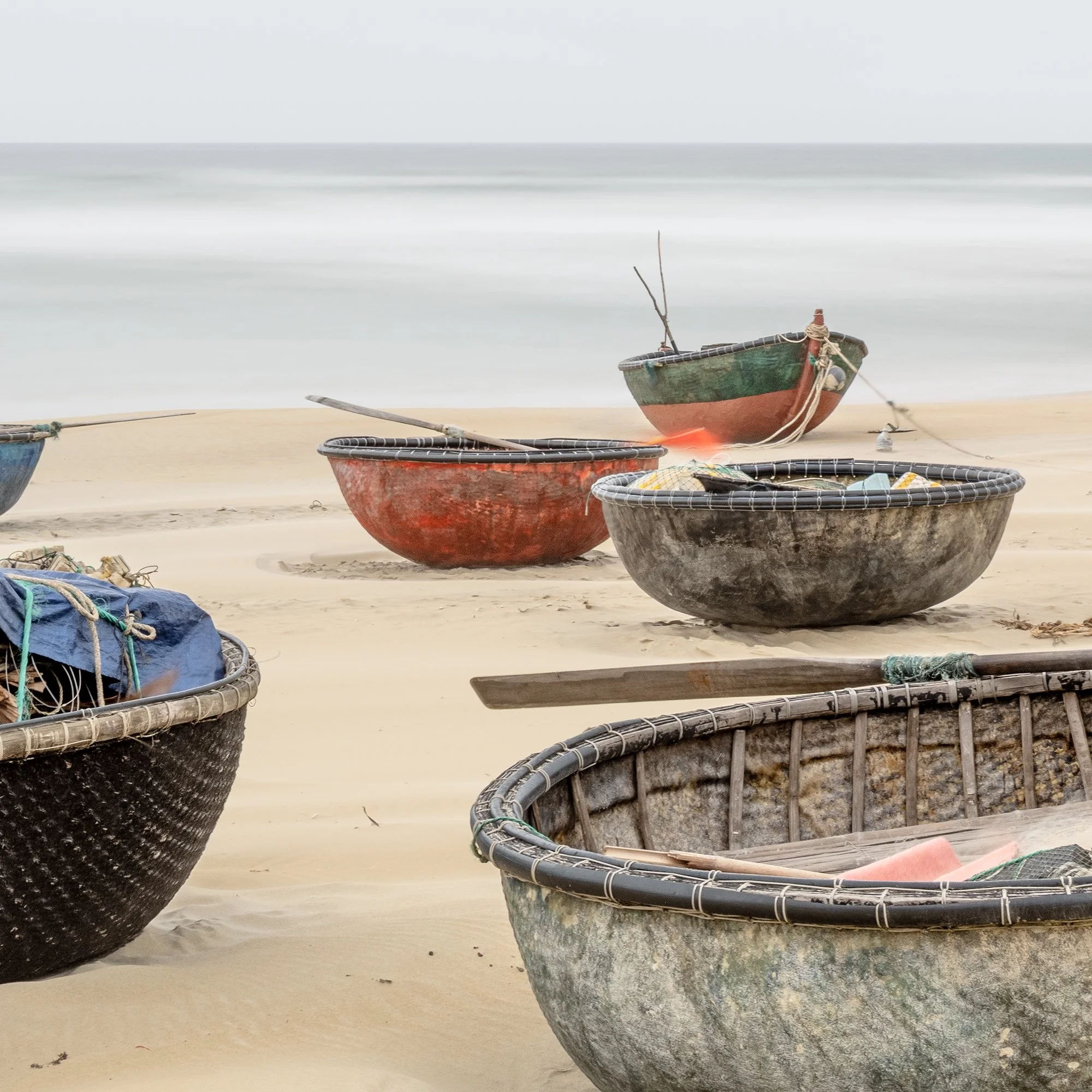 Gerald Berghammer - Color landscape photography. Several small boats resting on a sandy beach with calm ocean water under an overcast sky. Print detail 3