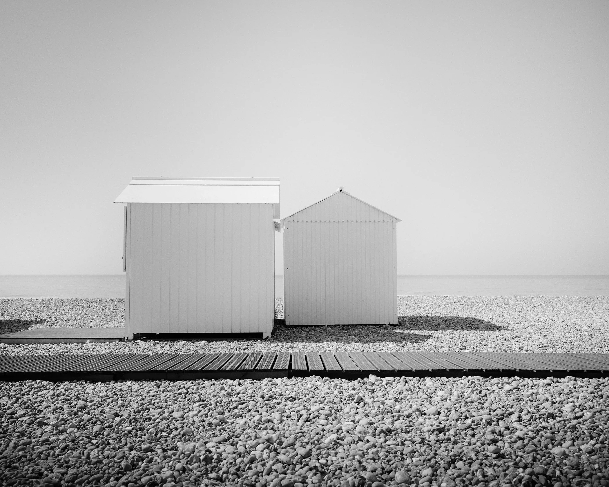 Esplanade Study 2 by Gerald Berghammer, minimalist black-and-white fine art photograph of two beach huts on the French coast.