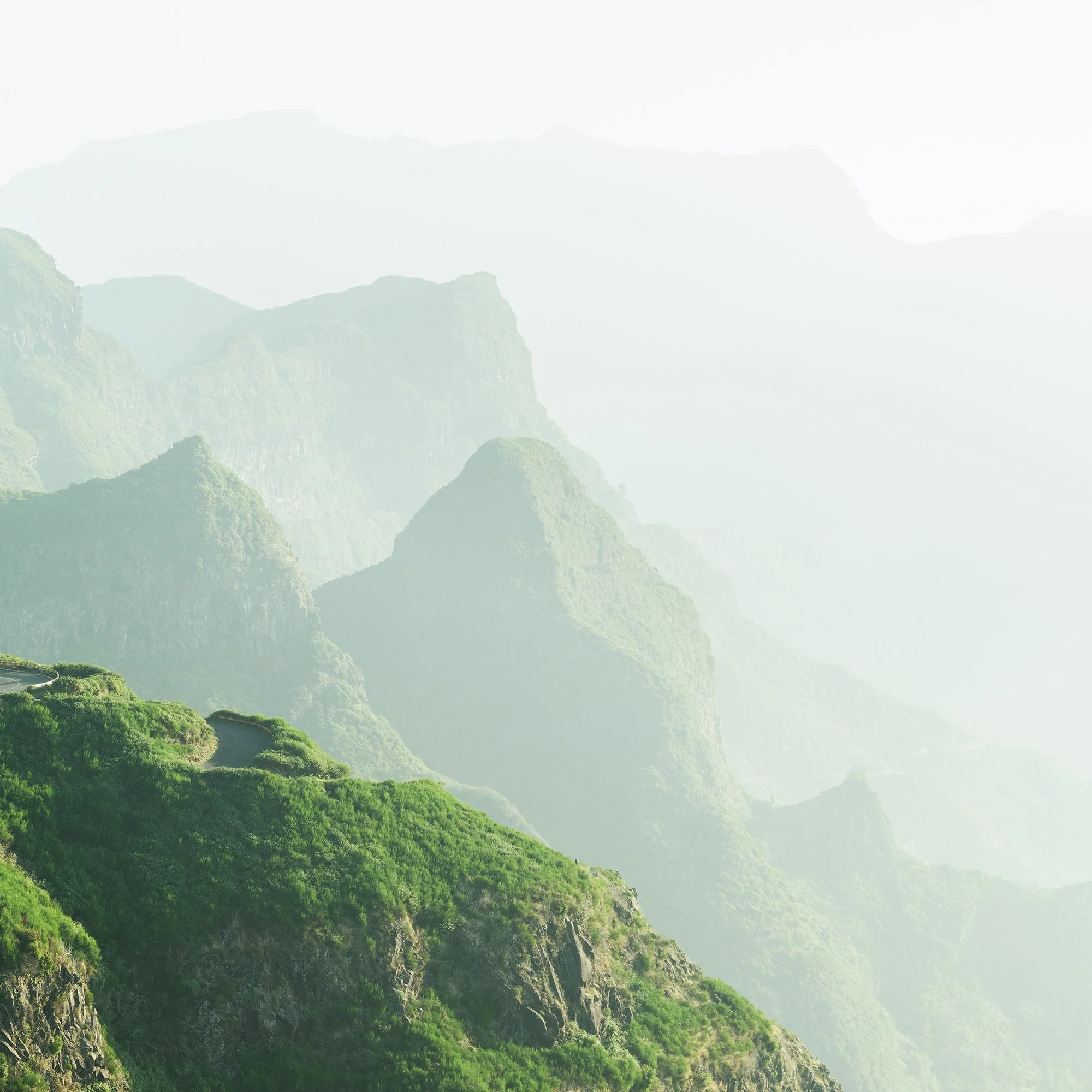 © 2021 Gerald Berghammer - Color Fine Art Landscape Photography. A winding mountain road through lush green cliffs and misty mountains in the background. Print detail 2