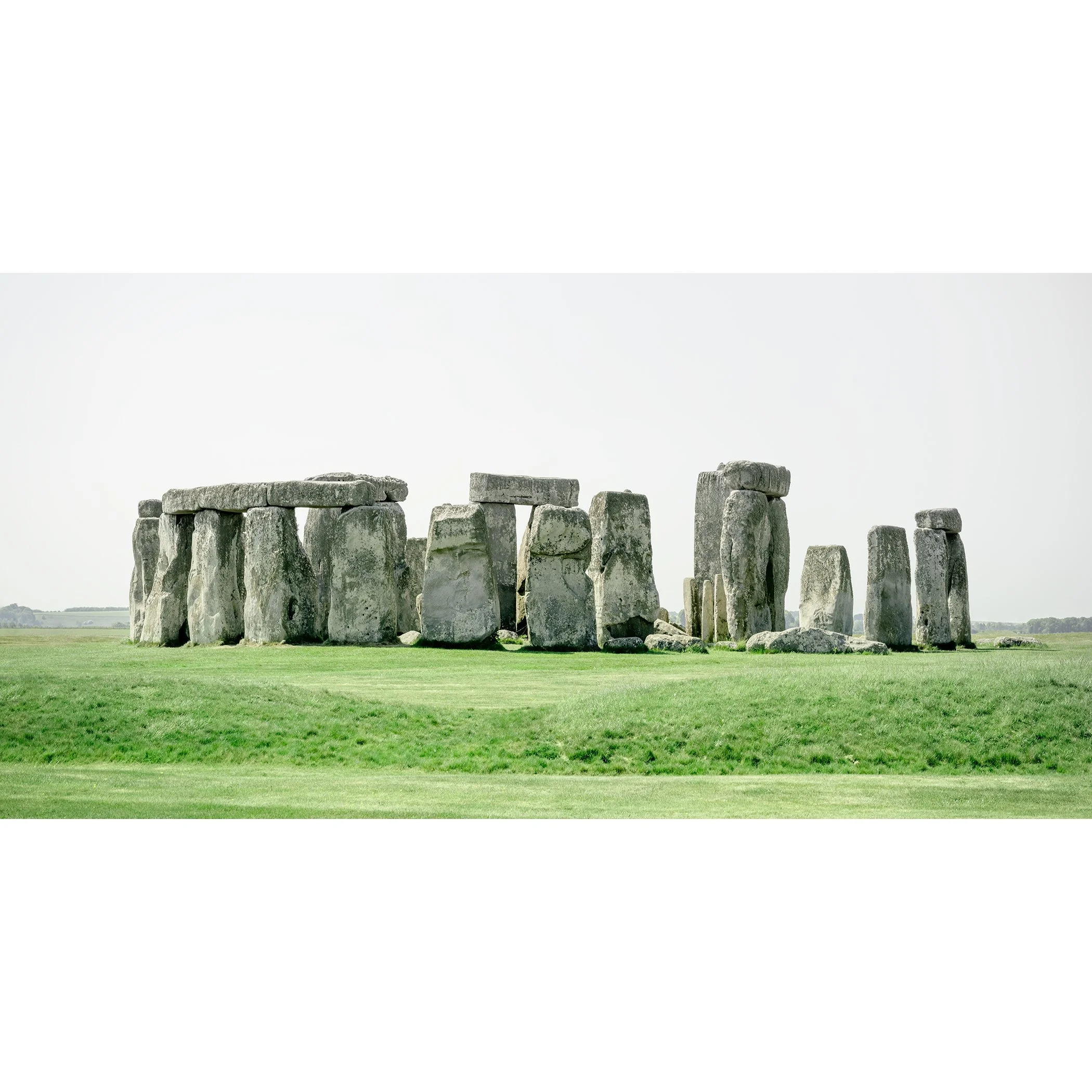 Gerald Berghammer - Color landscape panorama photography. Historic Stonehenge monument with large standing stones on a grassy field under a gray sky.