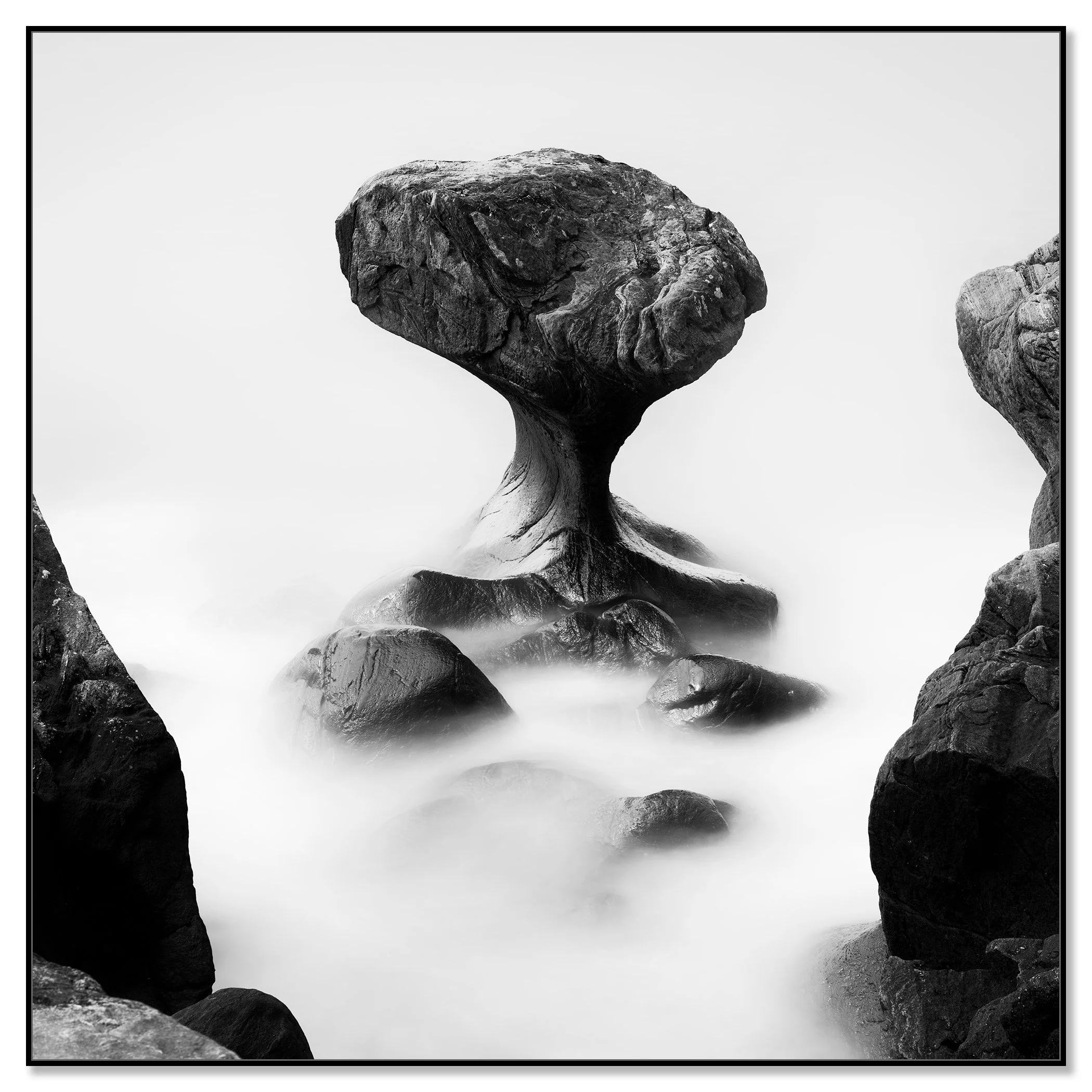Fine art monochrome image of an eroded sea stack in calm foggy water – framed ArtBox black