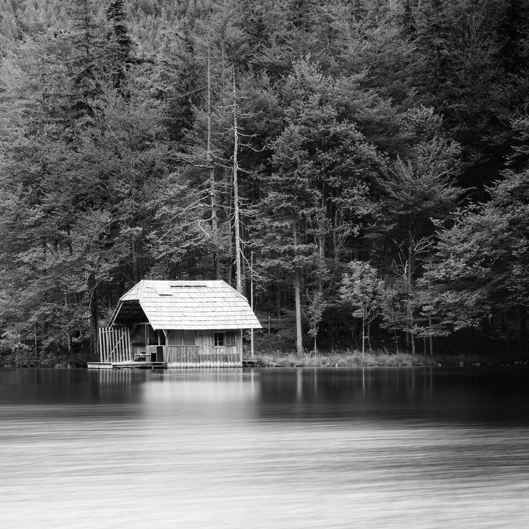 Closer view of the wooden boathouse and surrounding Alpine forest in Wooden Boathouse Panorama by Gerald Berghammer.