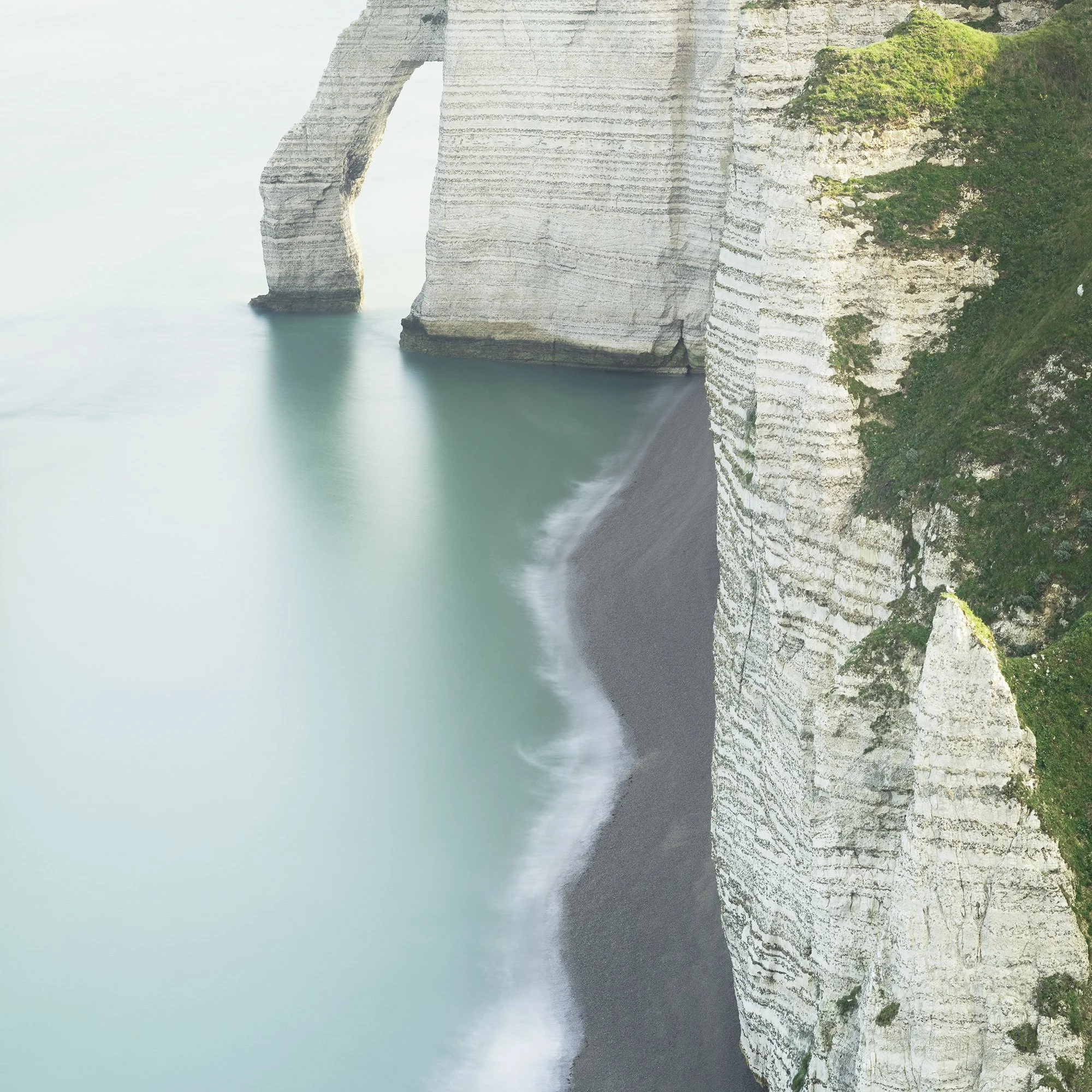 Detail of the misty shoreline and pale turquoise sea at Étretat, France