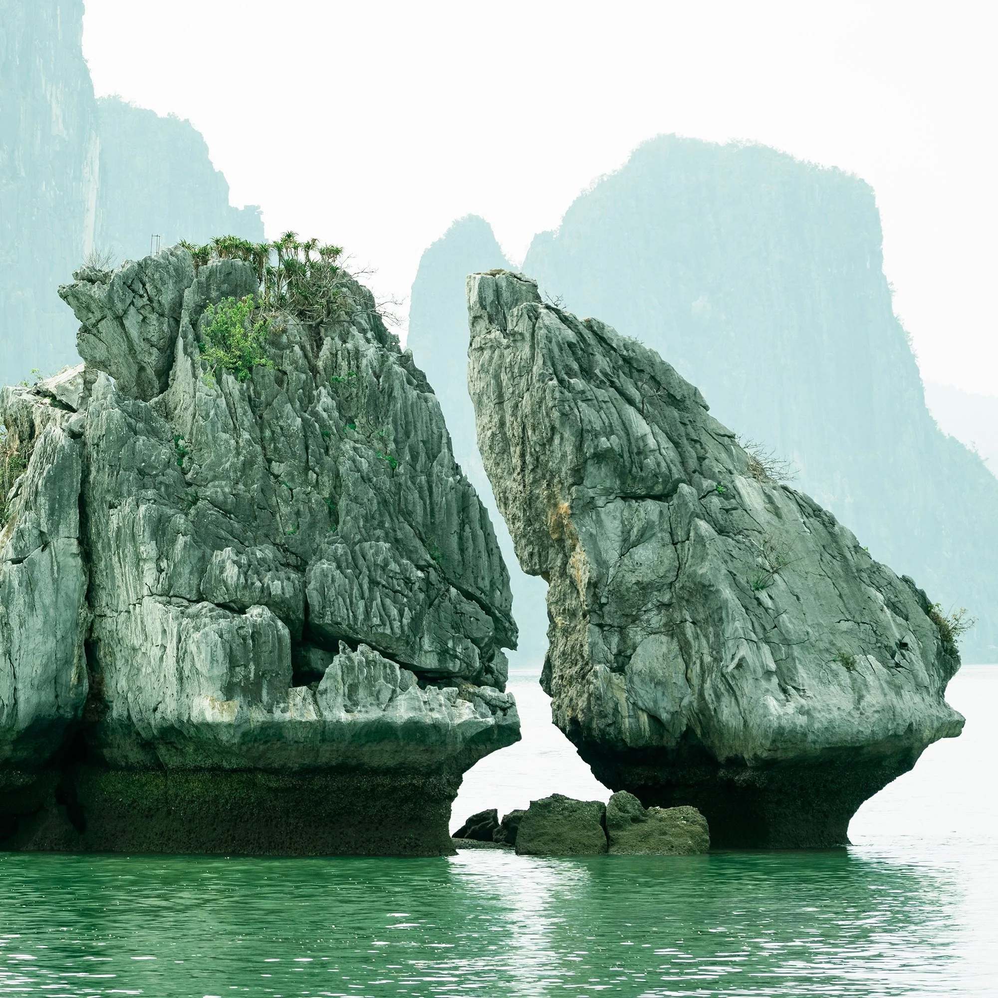 Gerald Berghammer - Color seascape photography. Large rocks rising from the water with, surrounded by calm water and distant limestone cliffs and islands. Print detail 3
