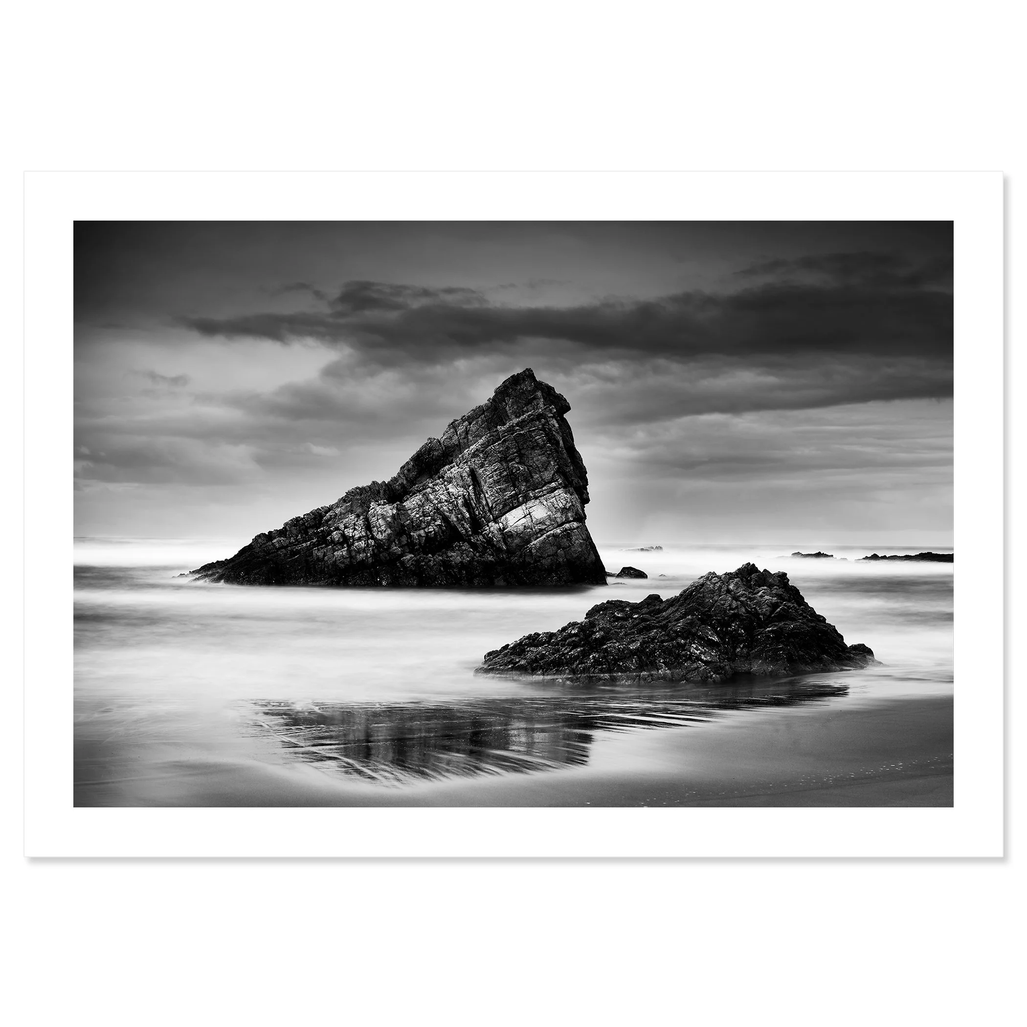 © 2023 Gerald Berghammer. Black-and-white photograph of jagged sea rocks emerging from calm water under a cloudy sky. Fine art print only