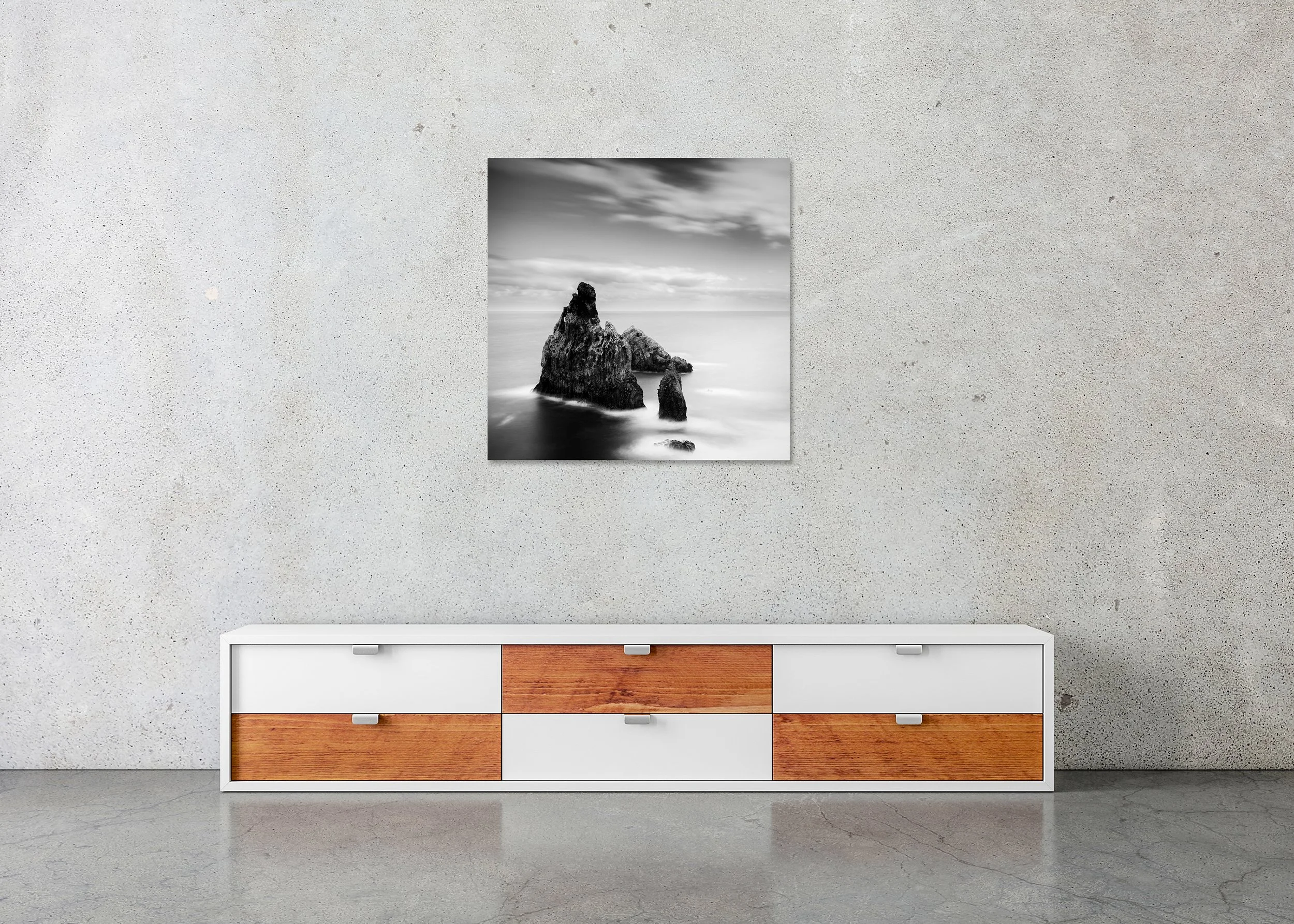 Black-and-white long-exposure photograph of rugged sea stacks emerging from a misty ocean beneath a soft, clouded sky, printed on frameless ChromaLuxe metal.