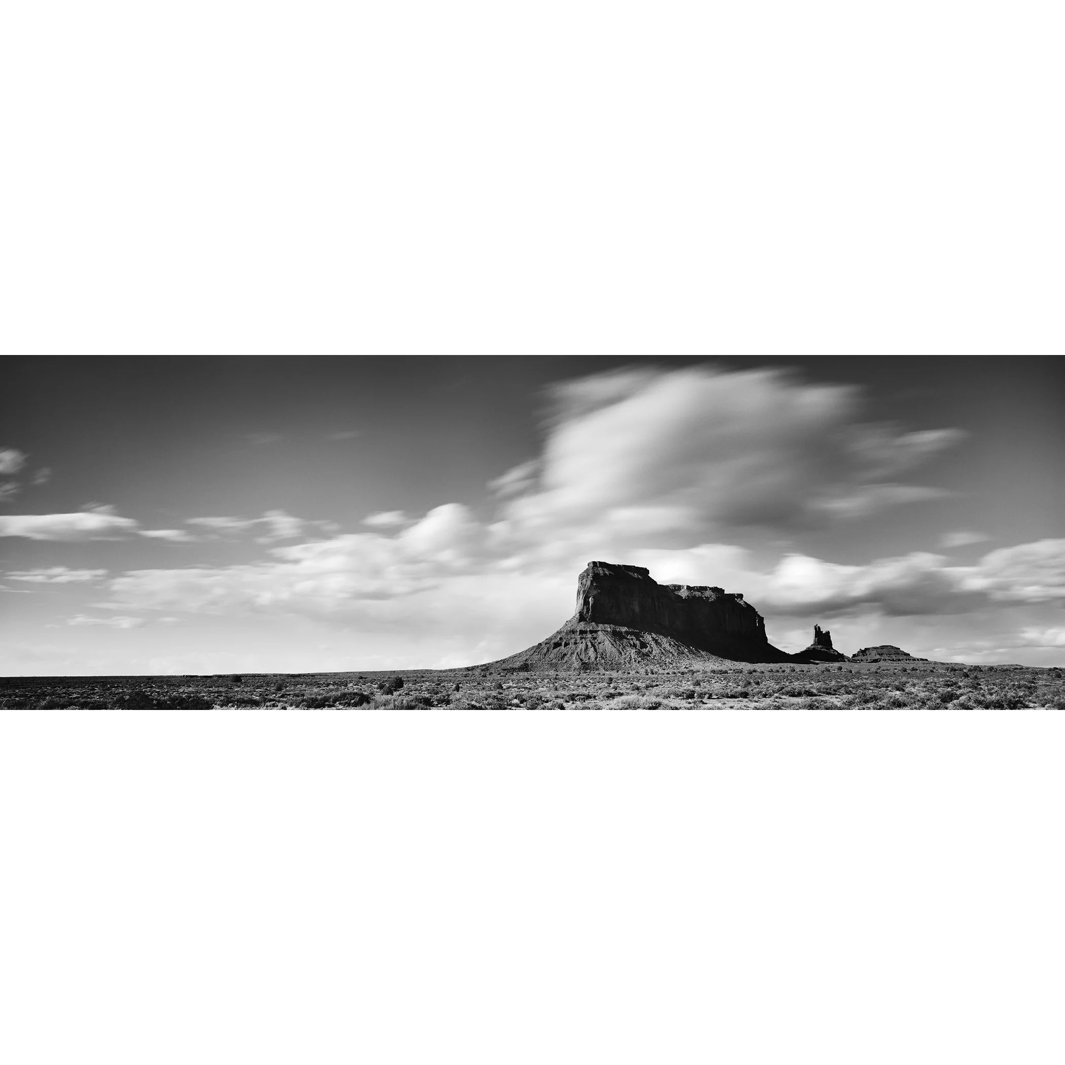 Gerald Berghammer - Black and white panorama desert photography. Flat-topped mesa with a smaller rock formation nearby, under a sky with scattered clouds.