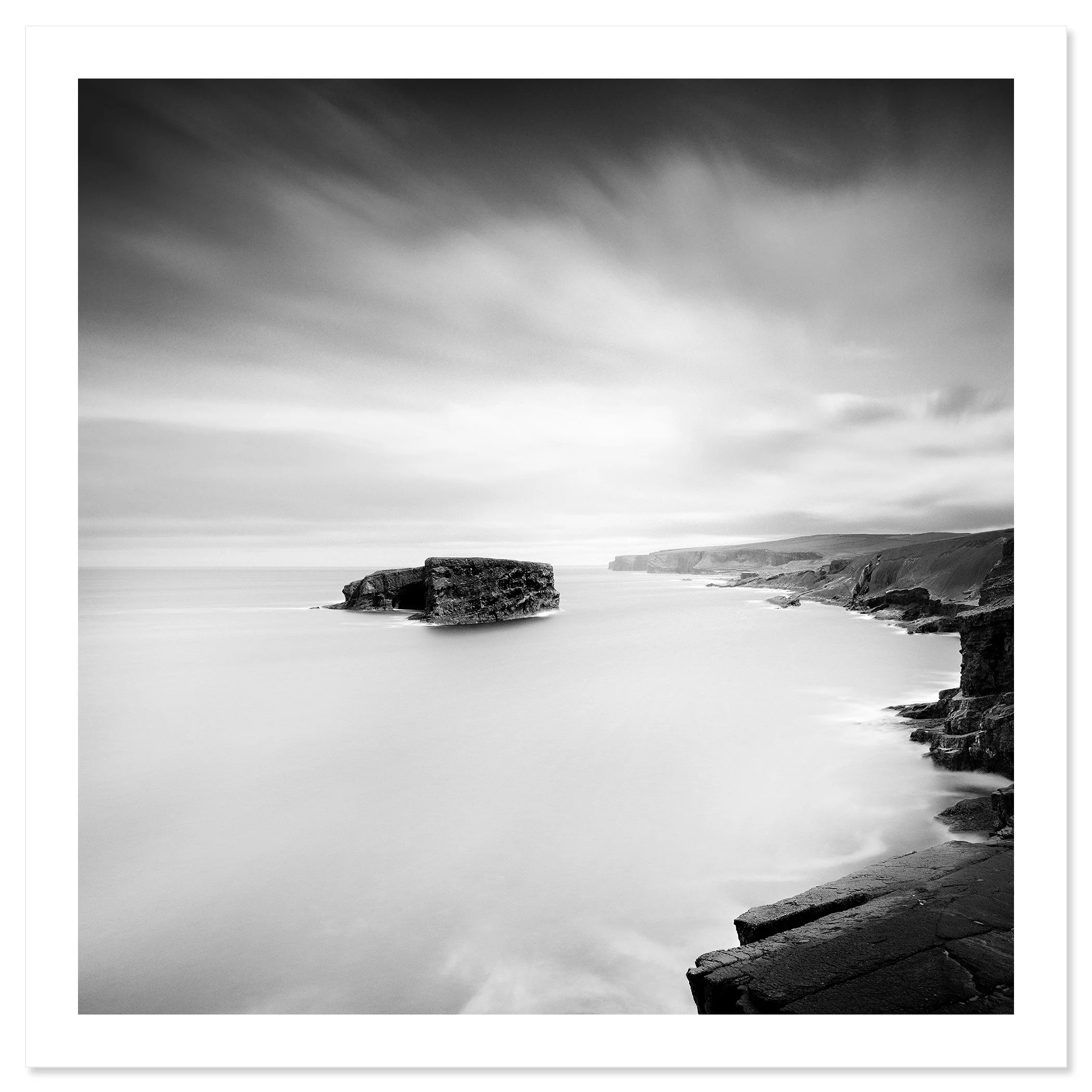 Gerald Berghammer - Black and white long exposure seascape photography. Rocky coastal landscape with cliffs and a large rock formation in the ocean. Fine art print only