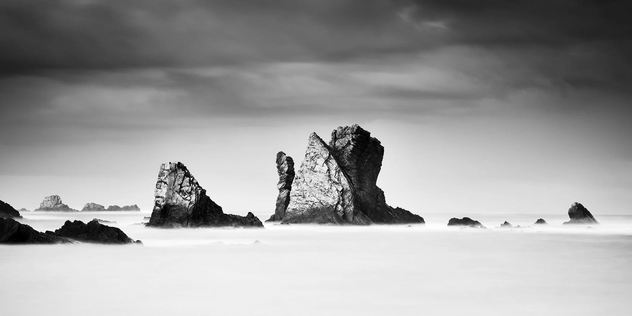 Black-and-white long-exposure photograph of monumental sea stacks at Silencio Beach, Spain, by Gerald Berghammer.