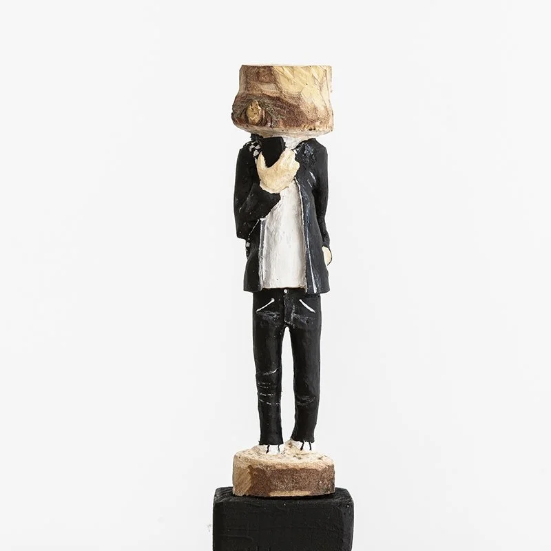 Figurative wooden sculpture of a standing person in black and white by Austrian artist ToPu – Thomas Pusswald.