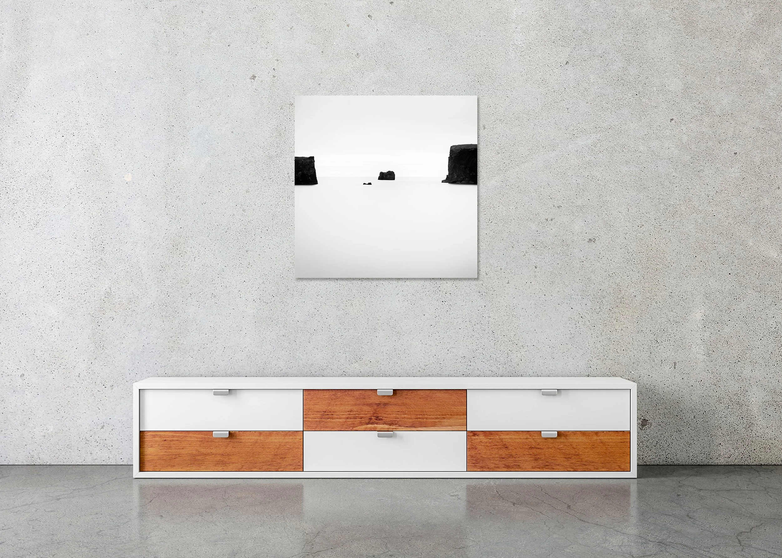 Minimalist black-and-white ocean photograph with three dark rock formations and distant sea cliffs, photo print mounted to Dibond, frameless.