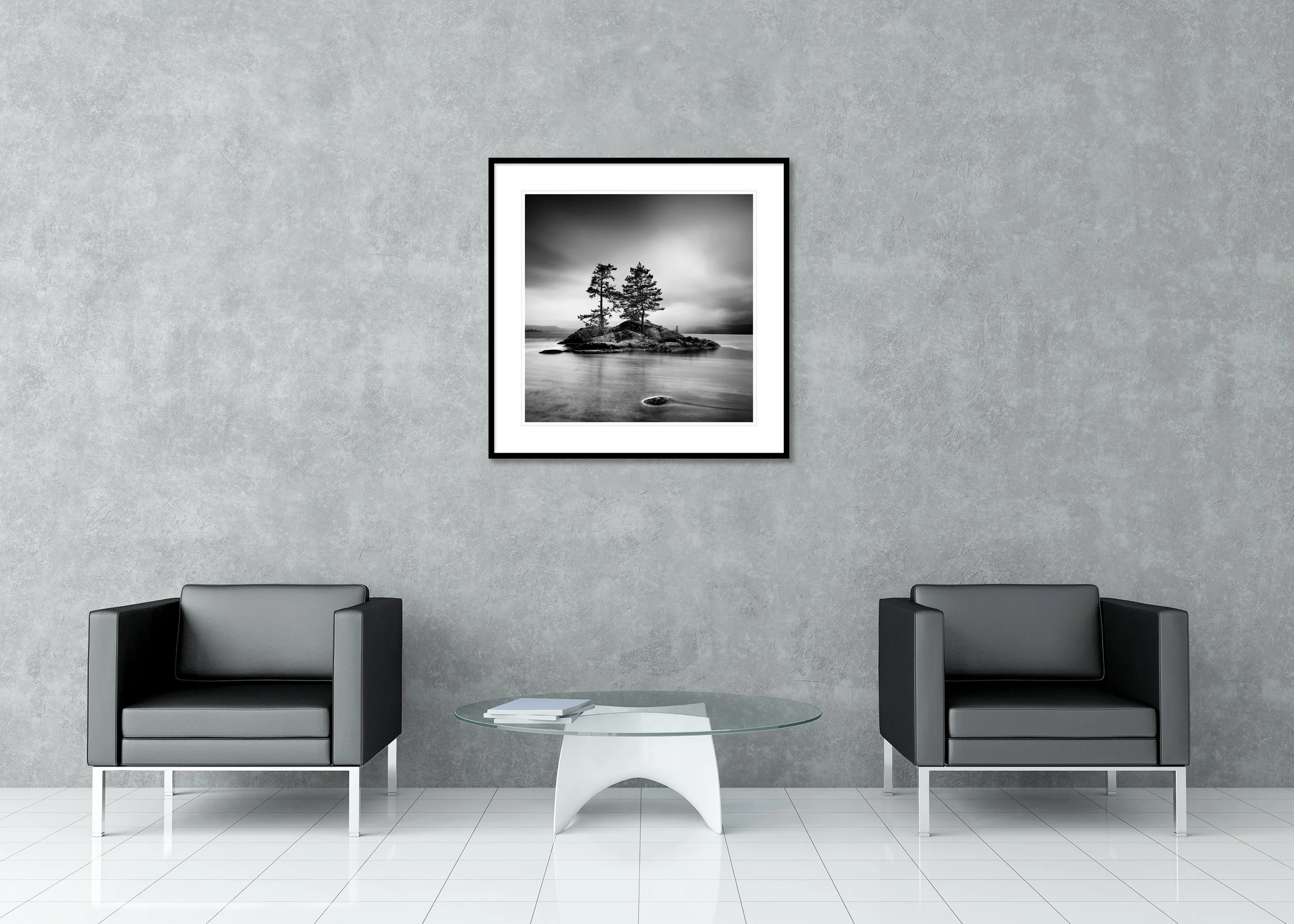 Black and white landscape print of two pine trees on a rocky island in a calm lake under a cloudy sky, archival pigment print in a classic frame with mount