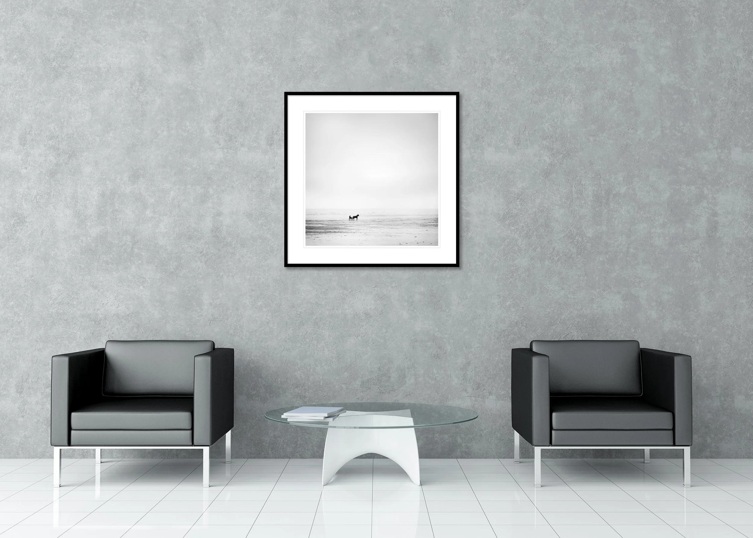 Minimalist black-and-white photograph of a horse pulling a small cart across an empty beach beneath a vast, foggy sky, presented as an archival pigment print in a classic frame with passe-partout.