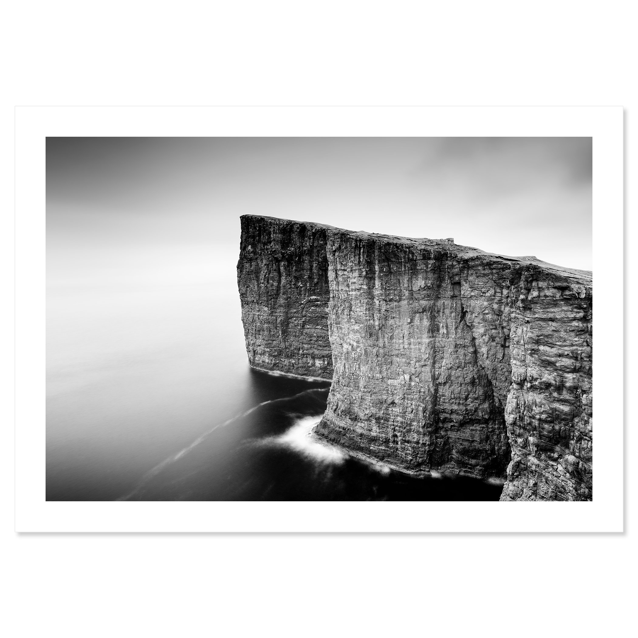 Gerald Berghammer - Black and white long exposure seascape photography. Tall, rugged cliffs by the ocean, waves crashing at the base, with a misty sky. Fine art print only